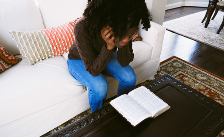 woman sitting on sofa reading Bible