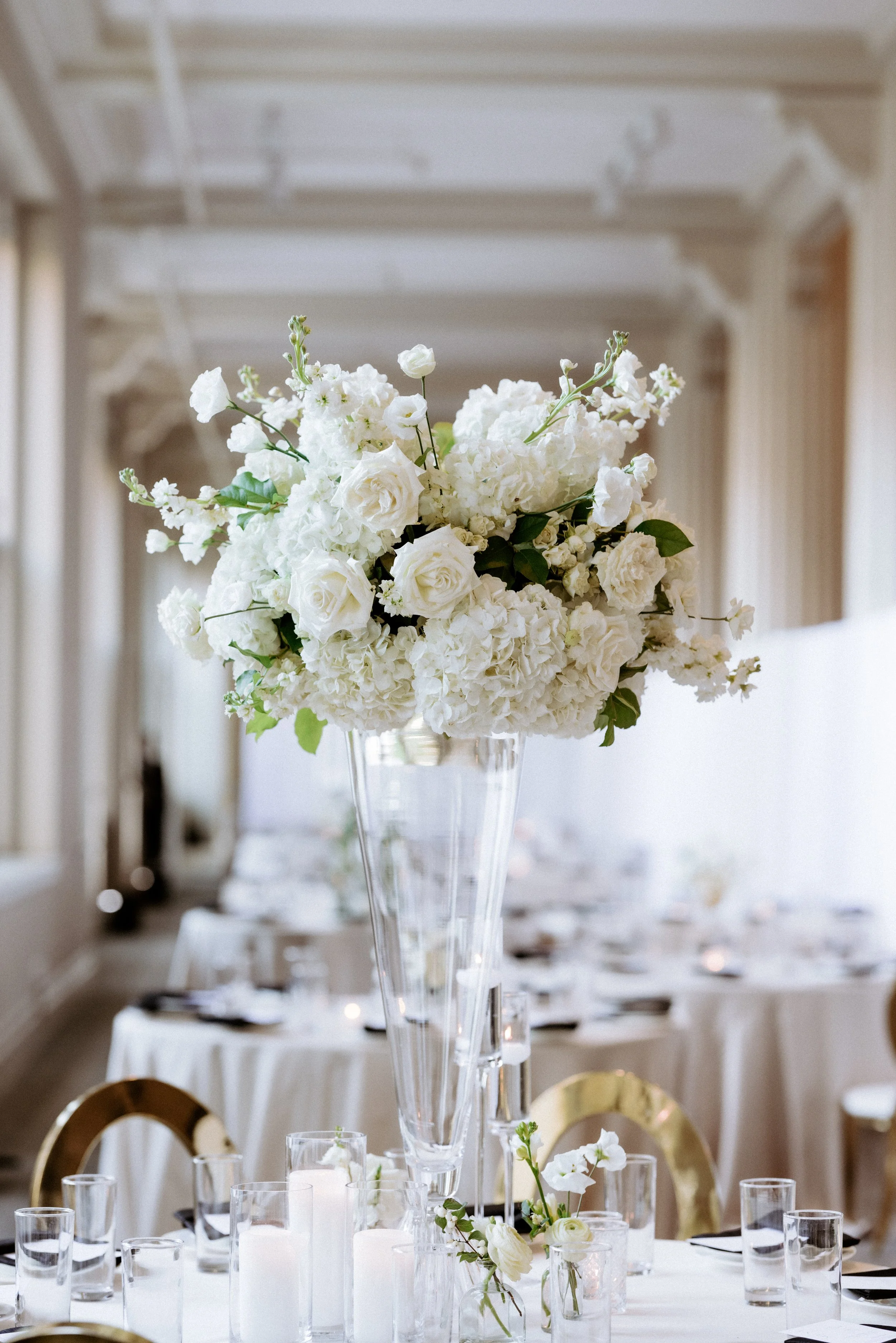 Classic tall floral centerpieces in elegant glass vases at The Corinthian Houston wedding reception.