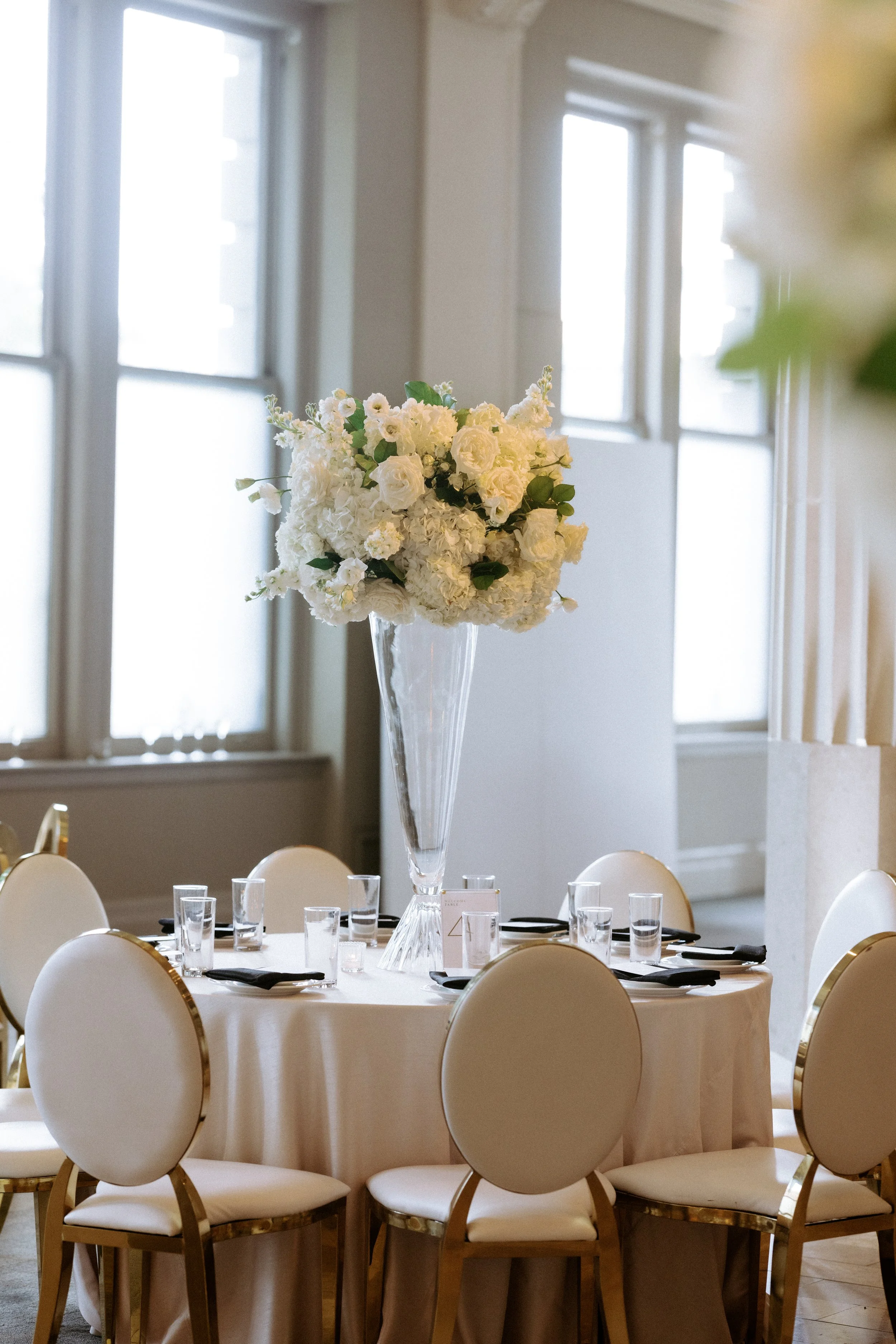 Classic tall floral centerpieces in elegant glass vases at The Corinthian Houston wedding reception.