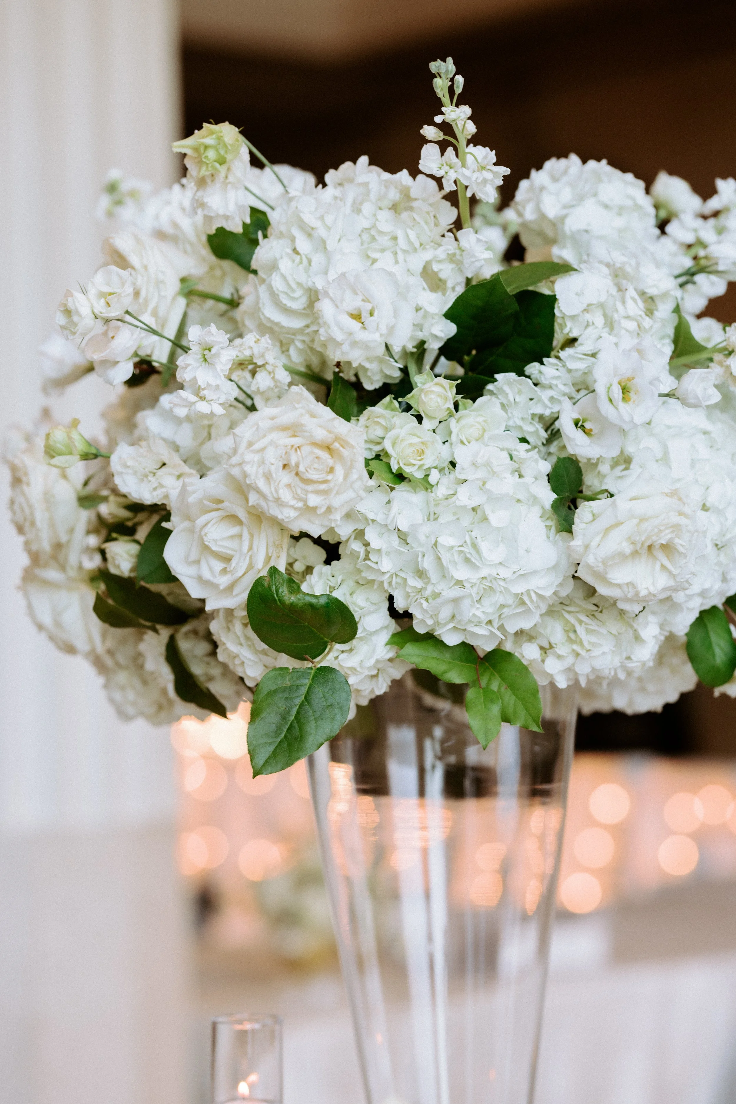 Classic tall floral centerpieces in elegant glass vases at The Corinthian Houston wedding reception.