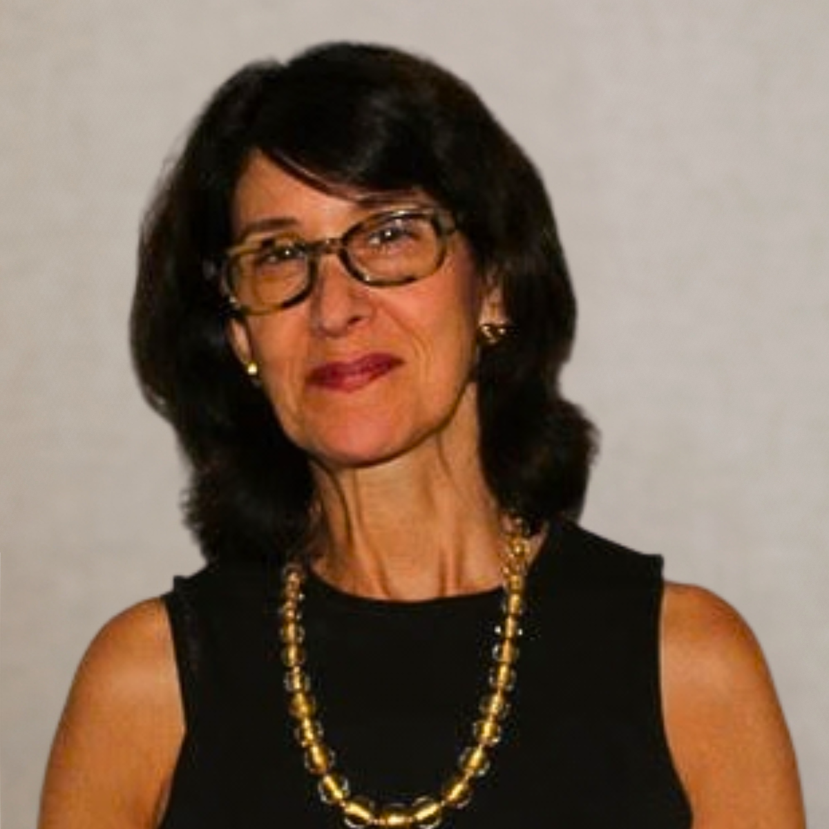 A woman with black hair smiling, wearing earrings.
