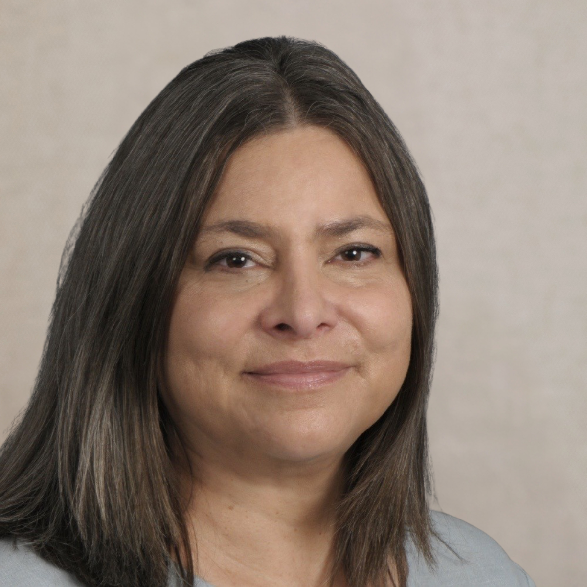 Close-up photo of a woman with straight brown hair, smiling softly, against a neutral gray background.