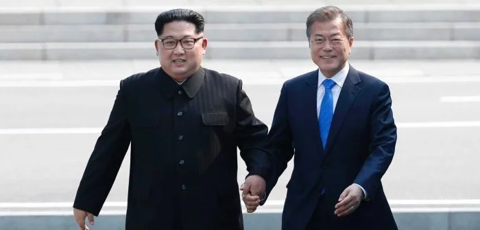 Kim Jong-un and Moon Jae-in hold hands as they cross the border into South Korean territory