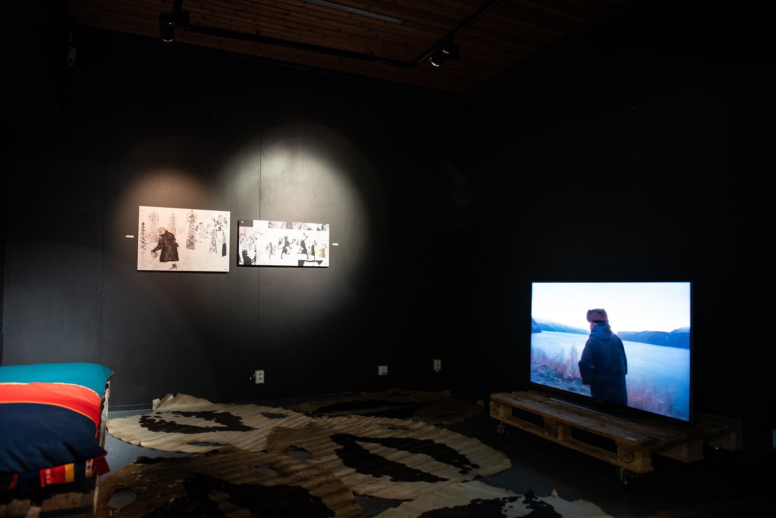  Máret Ánne Sara’s two mixed-media prints on the wall. Looping on the screen to the right is Joar Nango and Ken Are Bongo’s tv-series  Post-Capitalist Architecture-TV . Photo/Govven: Daniel Skog/Riddu Riđđu.  