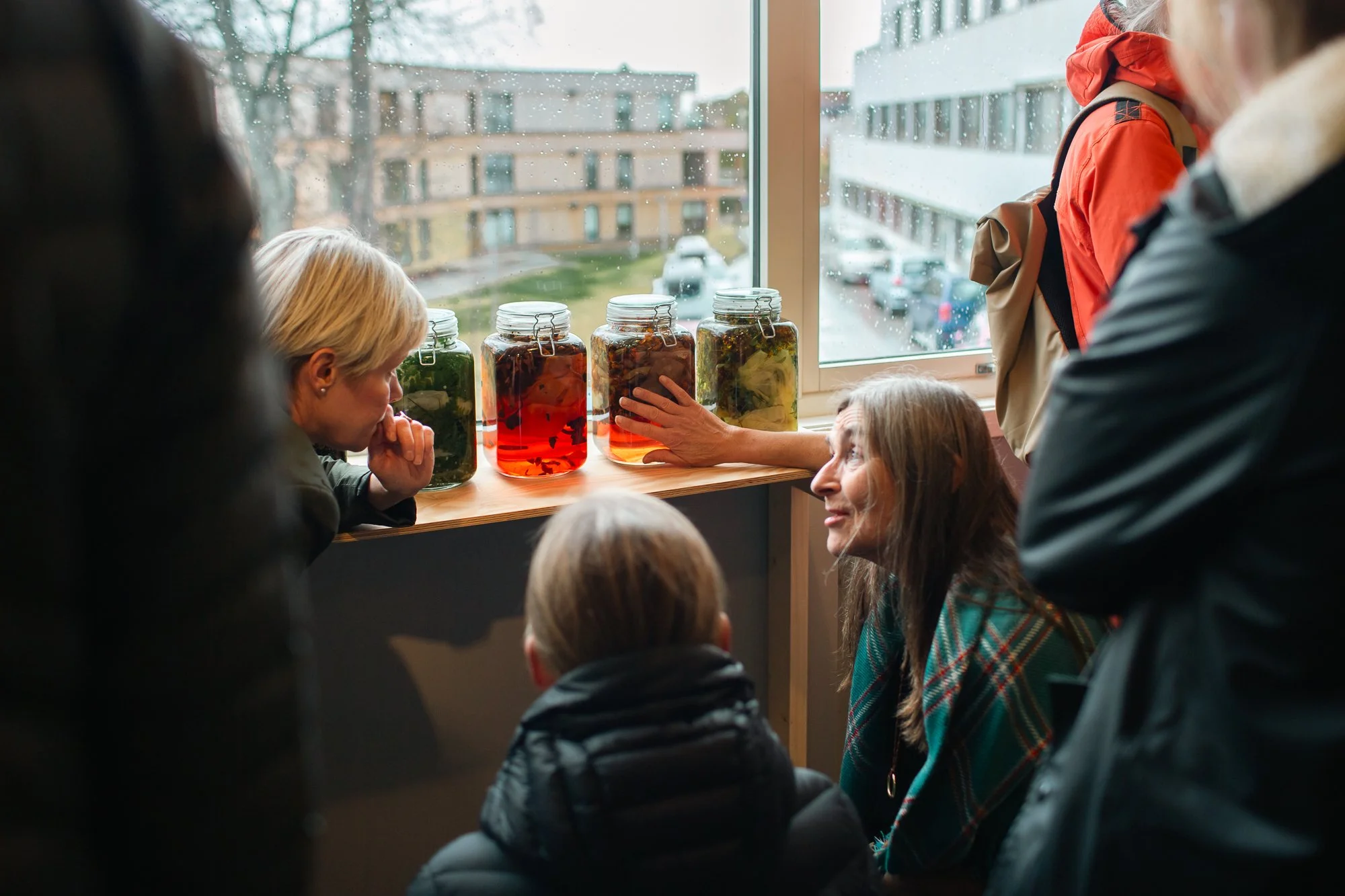  Hilde Hauan Johnsen at the opening of the exhibtiion, showing some visitors a part of her installation  Colour Prisms from Nature V . Photo: Daniela Toma / Tromsø Kunstforening 
