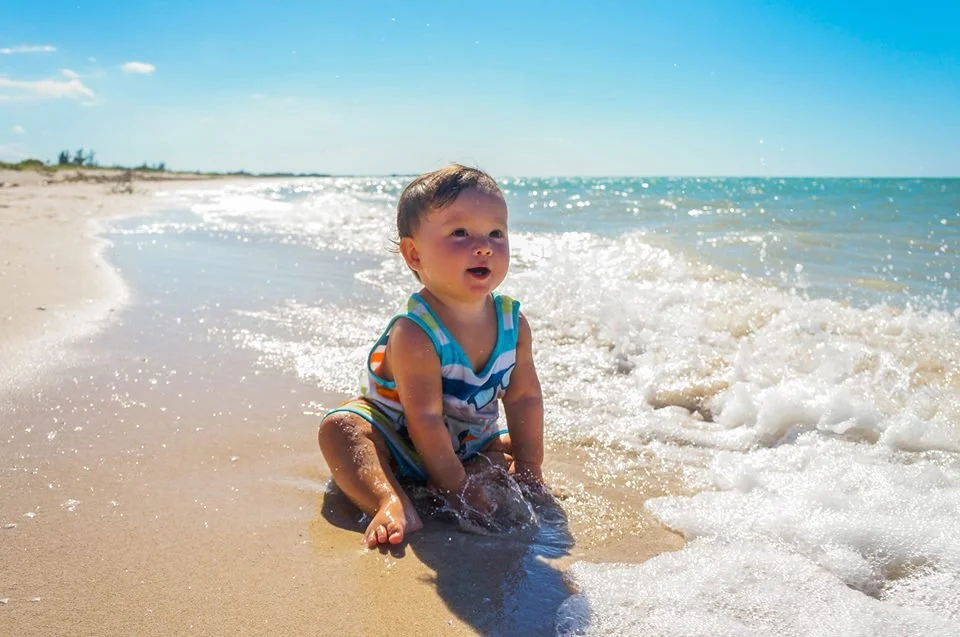 Baby playing in the waves on a Tulum beach — English-speaking vacation babysitter in Tulum
