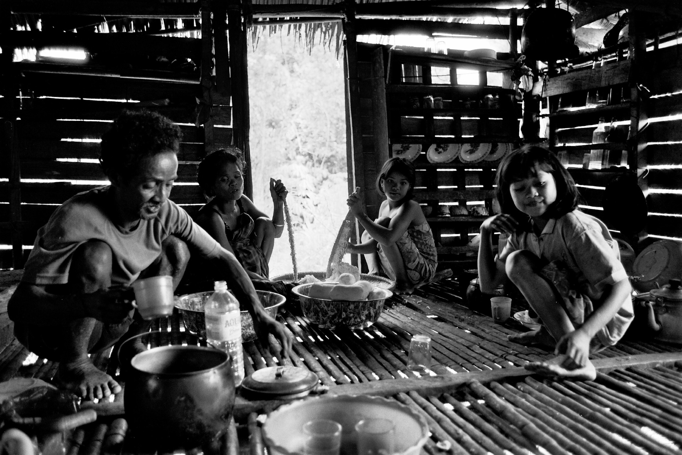 The man on the left is an elder, the women are preparing the bitter local root. (C)