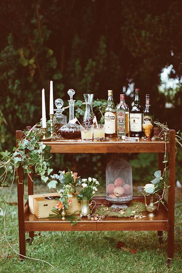 Relaxed help yourself wedding bar cart with foraged greenery and boho styling featured on One Fab Day .