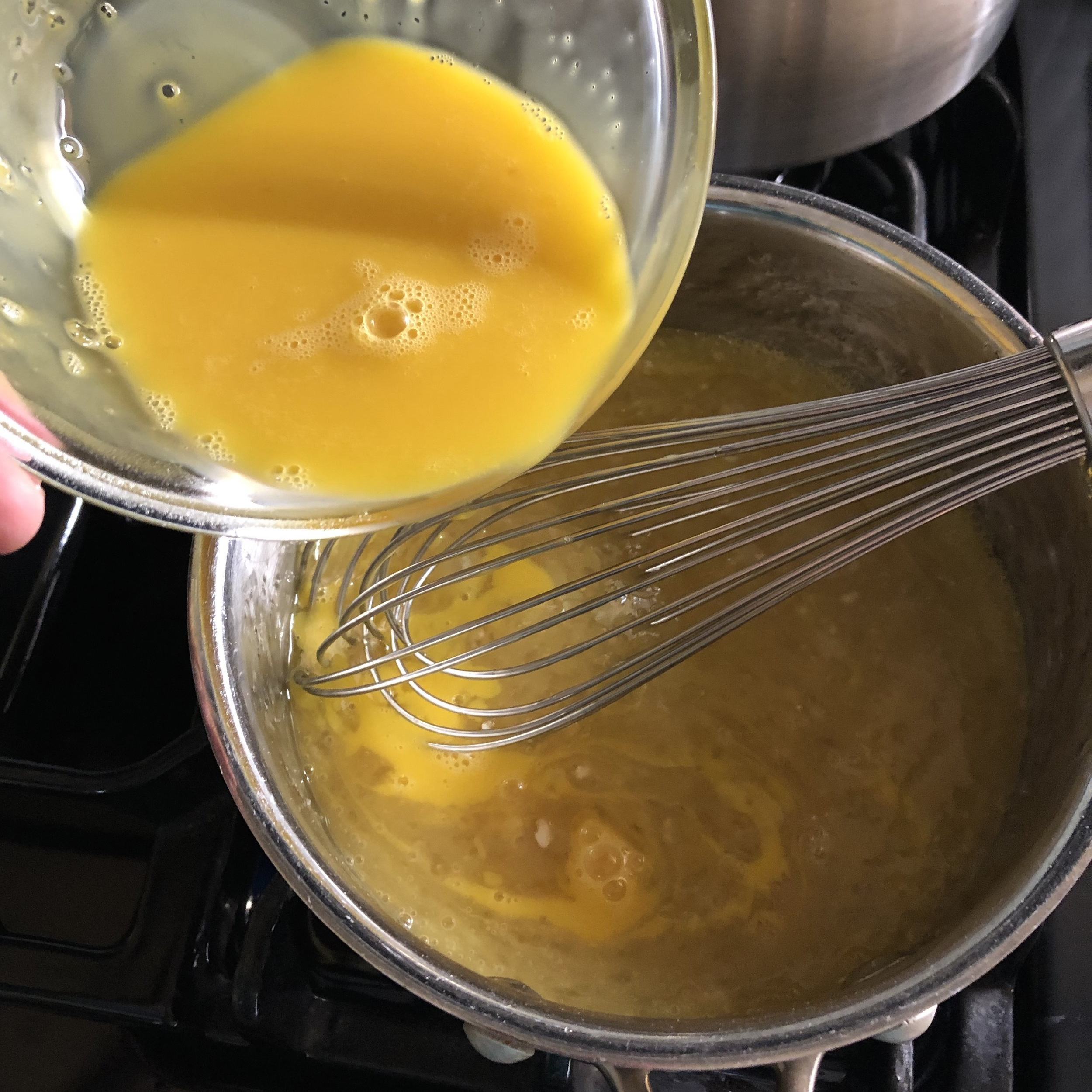  Temper eggs to avoid scrambling them. After whisking a small amount of the hot liquid into the egg yolks, slowly whisk the egg yolk mixture back into the hot liquid. 