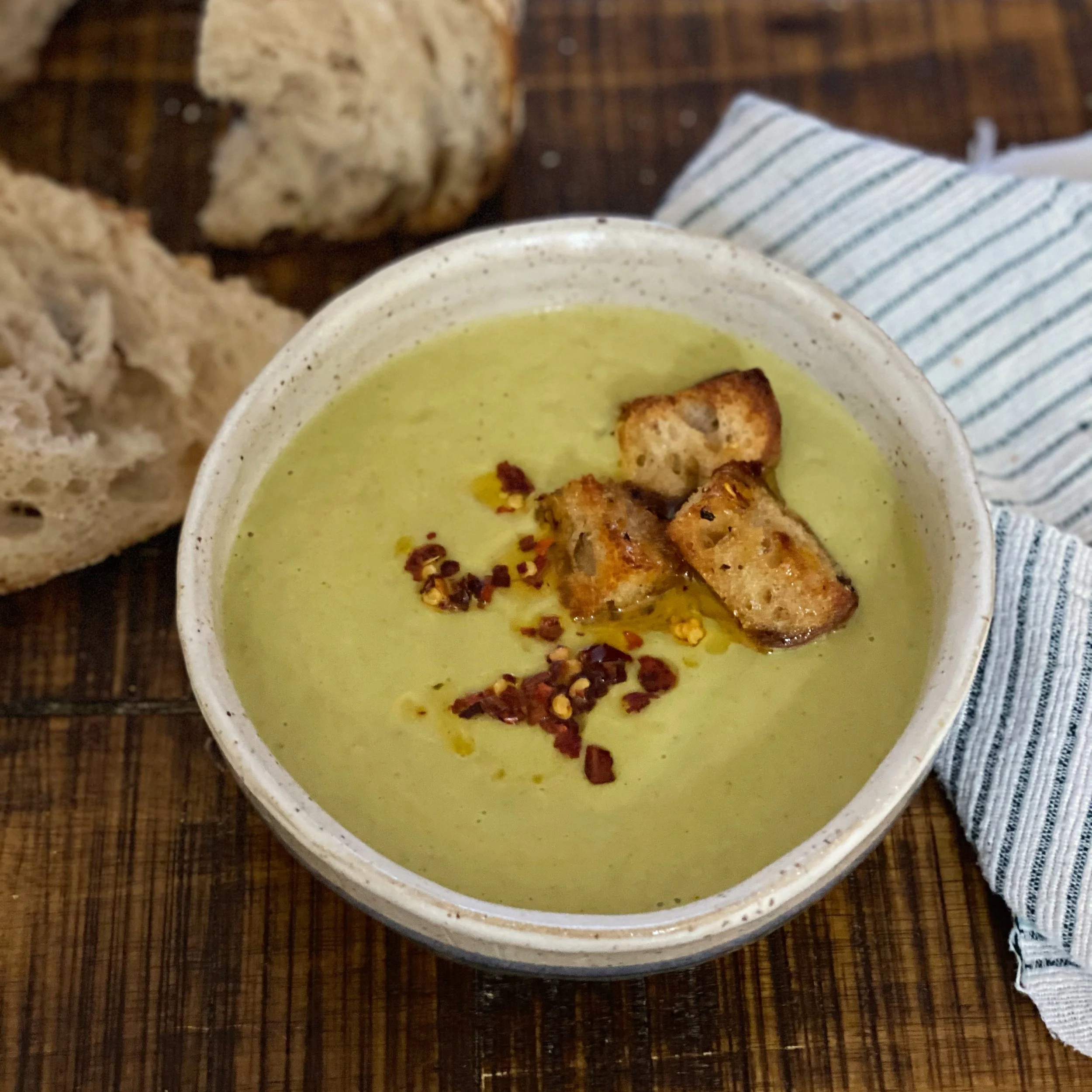 creamy green soup with croutons and spice oil.jpeg
