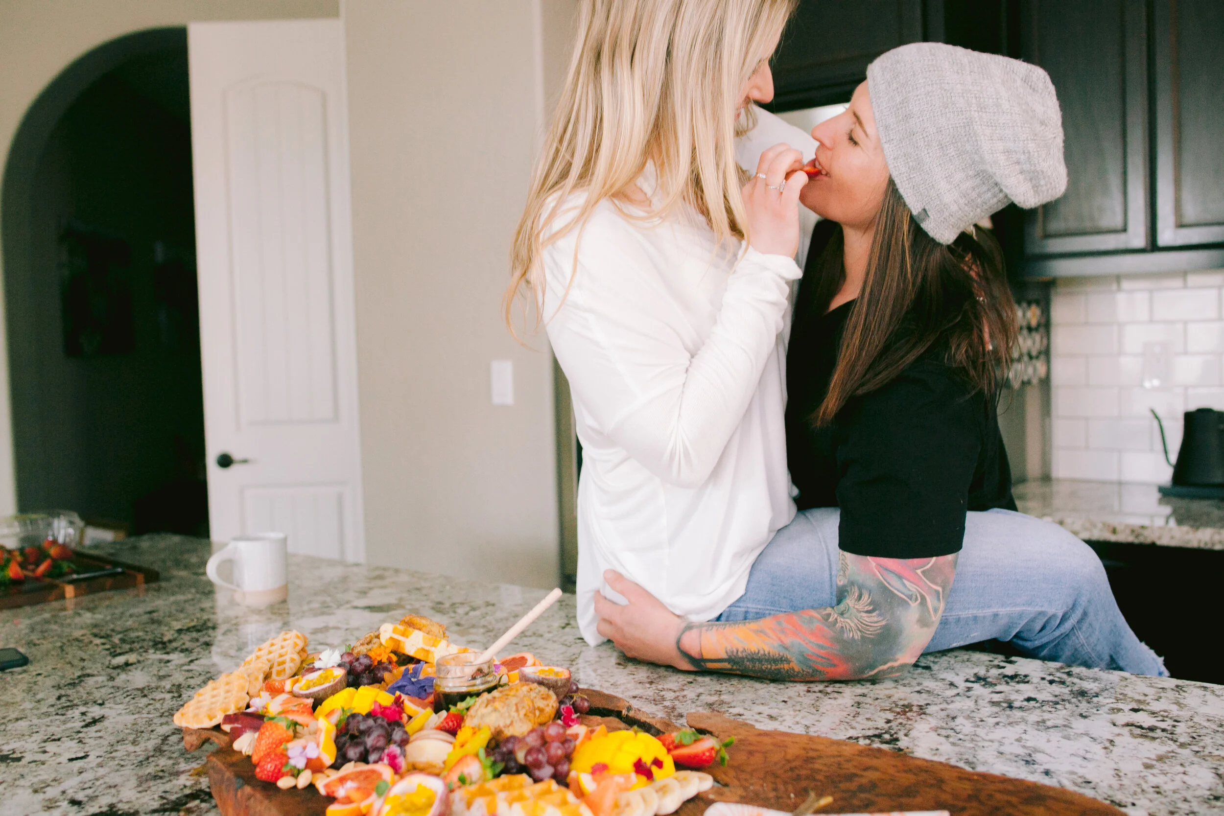 Two women feeding each other and laughing on top of counter