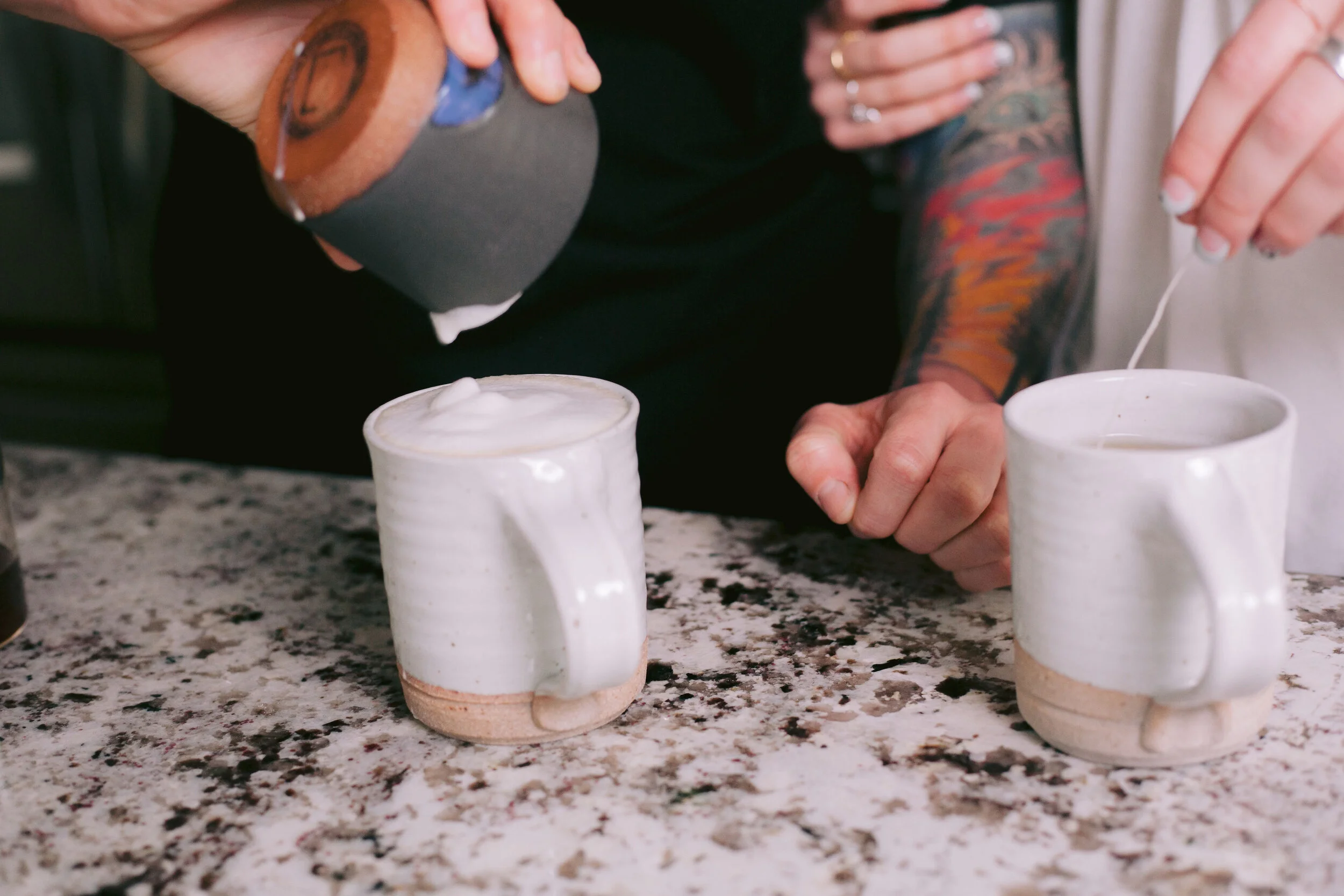 Woman pours the remainder foam onto latte in kitchen