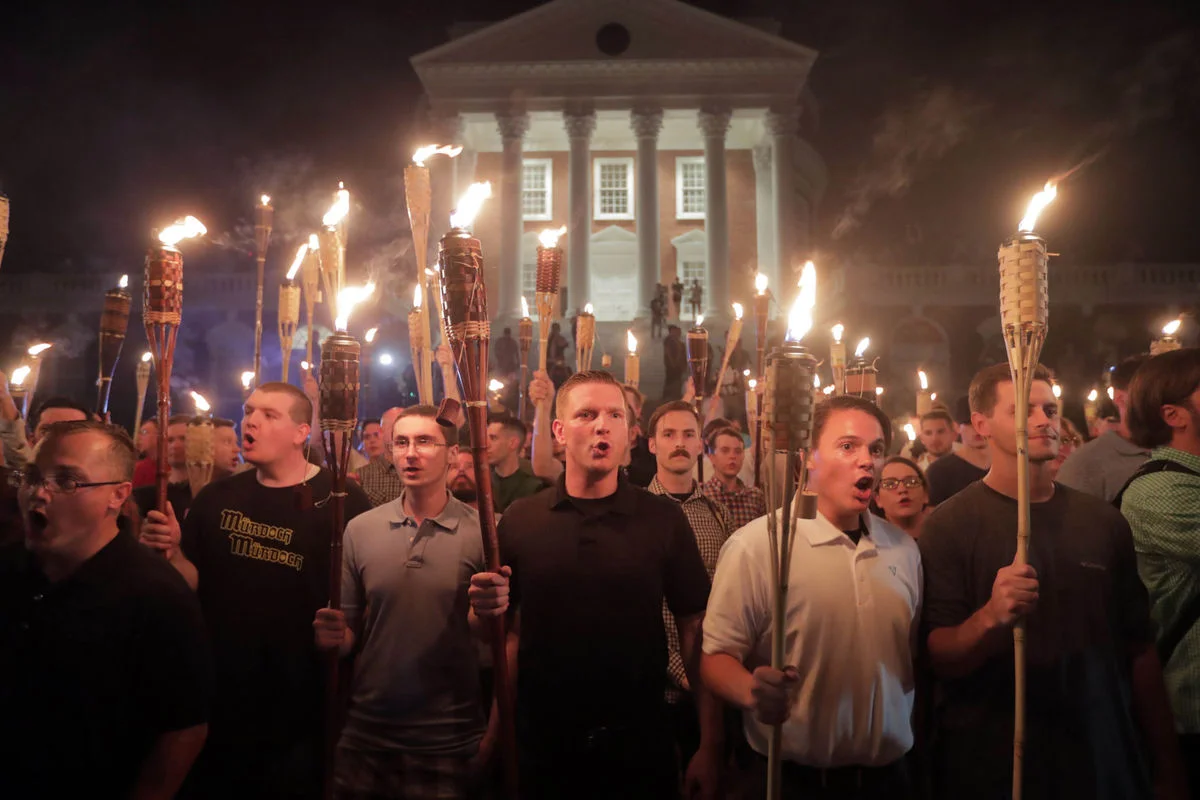 These are the monsters we mock. Young white men (probably a few older ones, mixed in, but that’s the only mixing), unaware of inadvertent comedy, clueless about the cartoon quality of tiki torches. They say the same vile shit their ancestors did, but they must know they’re extras in someone else’s film. Someone with more power, more authority, more vision. There’s no vision here, not a speck. Aargh. The ones who aren’t marching are also zombies. They’d never march, in fact, and in some cases they’re offended by this open hatred and puffed-up bigotry, although God knows they voted for it. Whether they have some rudimentary, lizard-brain notions of political philosophy and have picked one they like, or they’re just—as I suspect—passive receivers of whatever someone shoves onto their screens, they’re still the walking dead of our once impressive republic. The truth is out there, and it’s not hidden at Roswell. It’s where it always has been, in a well-disclosed location known as In Plain Sight, but these undead…boy, I don’t know. Their information-gathering skills seem limited by their cable subscriptions and car radios, and how easy was that, Mr. Murdoch? Give them biases that are totally confirmatory of their worst fears, then tell them THIS IS THE ONLY TRUTH. DON’T BELIEVE ANYONE ELSE. And they don’t. Of course. So maybe they’re lost, doomed to shuffle the landscape in search of brains, a natural instinct, if apparently hopeless. Nature abhors a vacuum, and I assume their crania are already being filled with non-white matter, the way my basement has all those books. Apologies to books. These shuffling paleo-people, the ones in the photo, who might as well be wearing T-shirts that proclaim their inability to get a prom date? Nothing but fodder, drones in a battle that they can’t possibly grasp with their tiny hands. Annoying, alarming, and capable of great mischief, they’re unaware of their irrelevance for anything but distraction while power plays alone. So we get distracted, and the showrunners get more rich and more powerful. We sometimes, even, willingly toss coins their way, buy their wares, watch their “news” and their reality television, unaware that we’re forging our own nails for our own coffins. Oh, it’s only The Bachelorette , we say. Harmless. It’s only a horoscope, or essential oils, or whatever fantasy we decided to invest in, because life is hard and awfully boring, anyway. They’ve always wanted to run the show. Their philosophy will always be in the minority, by definition, but their power is growing and now overwhelming. They see themselves as Randian road warriors, a tiny sliver of humanity that can actually do things, and in some ways they’re right. They know how to accumulate wealth and power, and their prophecies seem awfully self fulfilling now. They are now in ascendancy, they are quite often brilliant, and they have no souls, not really. It’s never been about the zombies. These wannabe Klansmen are just foot soldiers. It was always going to be about the vampires.