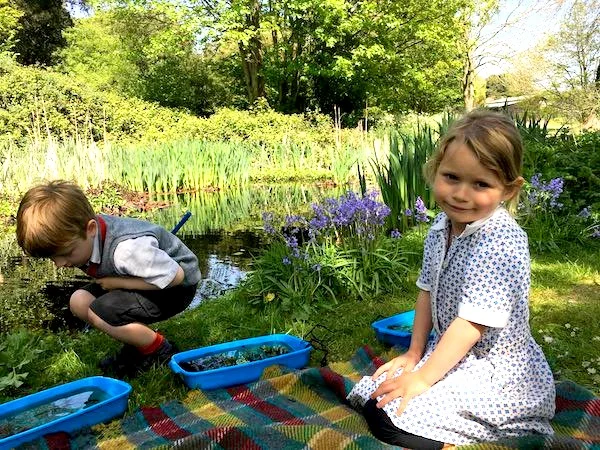 Children pond-dipping beside the large conservation pond at Sompting Abbotts