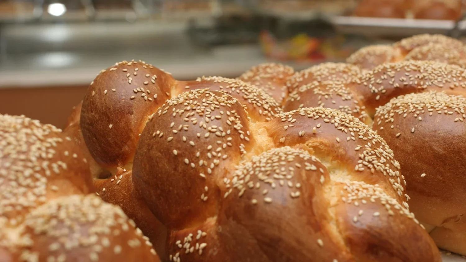 Close-up of freshly baked challah loaves topped with sesame seeds.webp