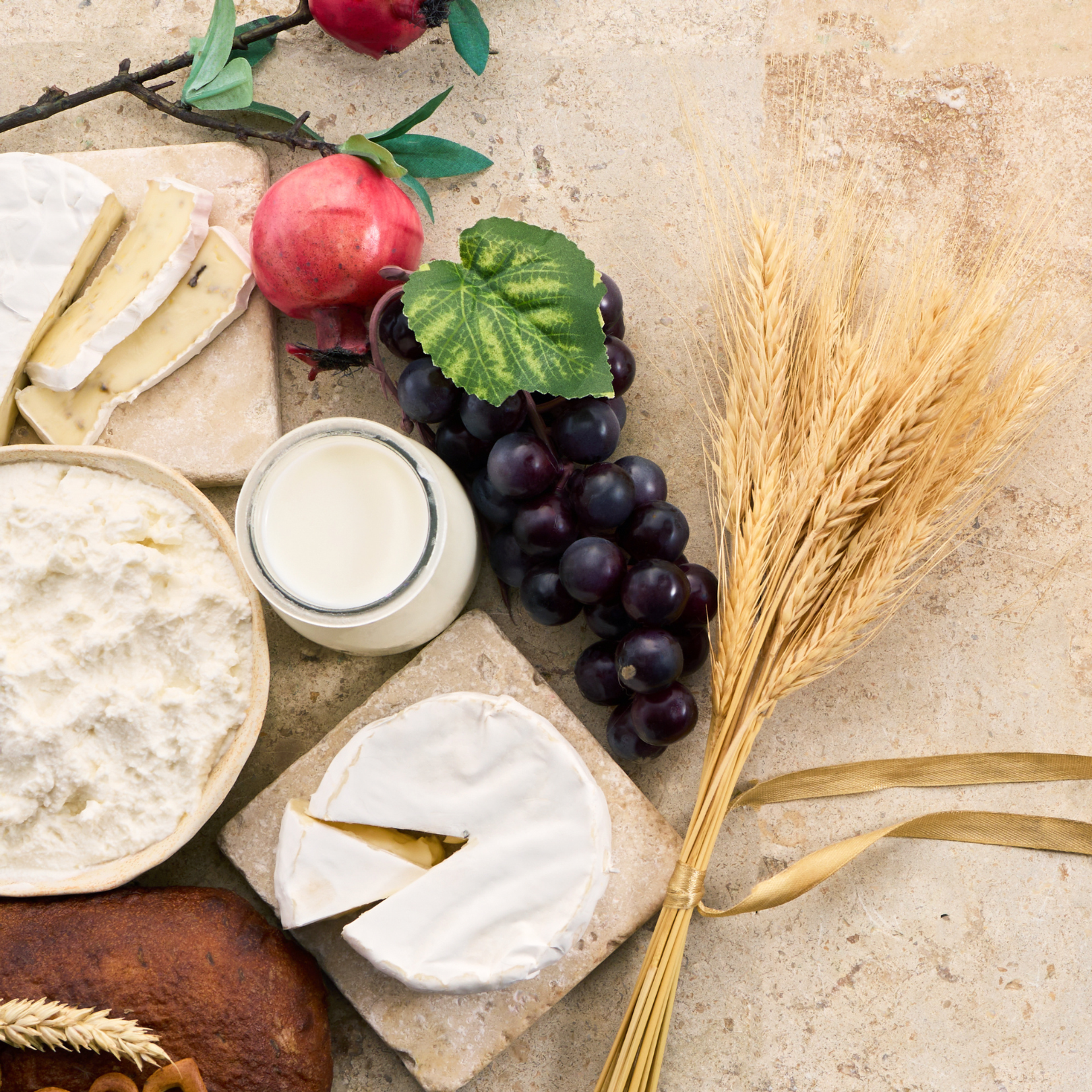 A granite slab featuring a spread of Shavuot food including fruit, milk, cream, cottage cheese and bread
