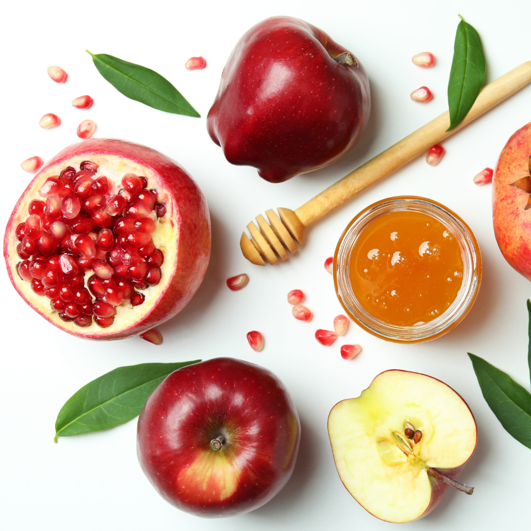 Rosh Hashana items on a White backgroun. Looking down at apple, pomegranate, and honey