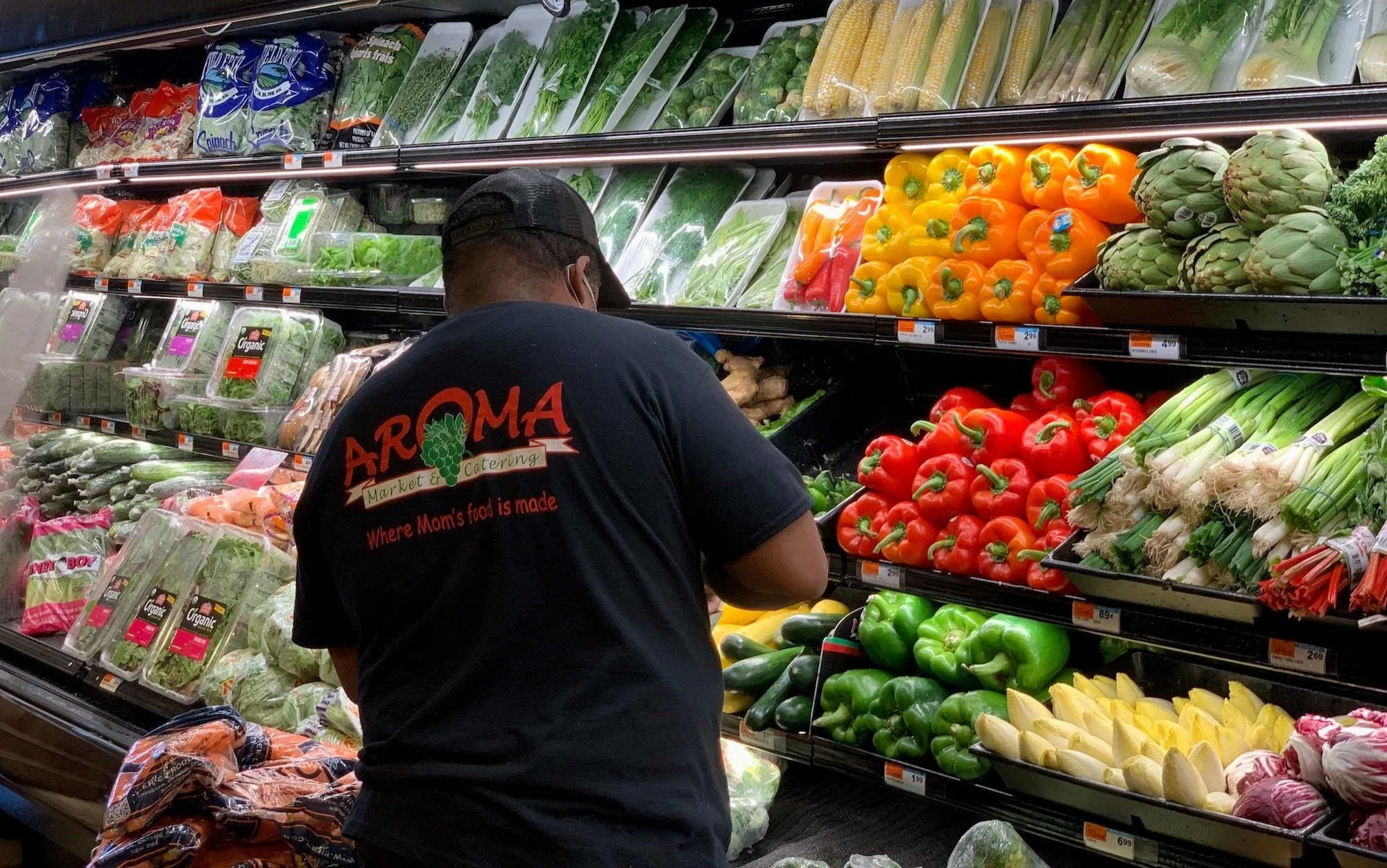 Employee organizing the colorful fresh produce display at Aroma Market