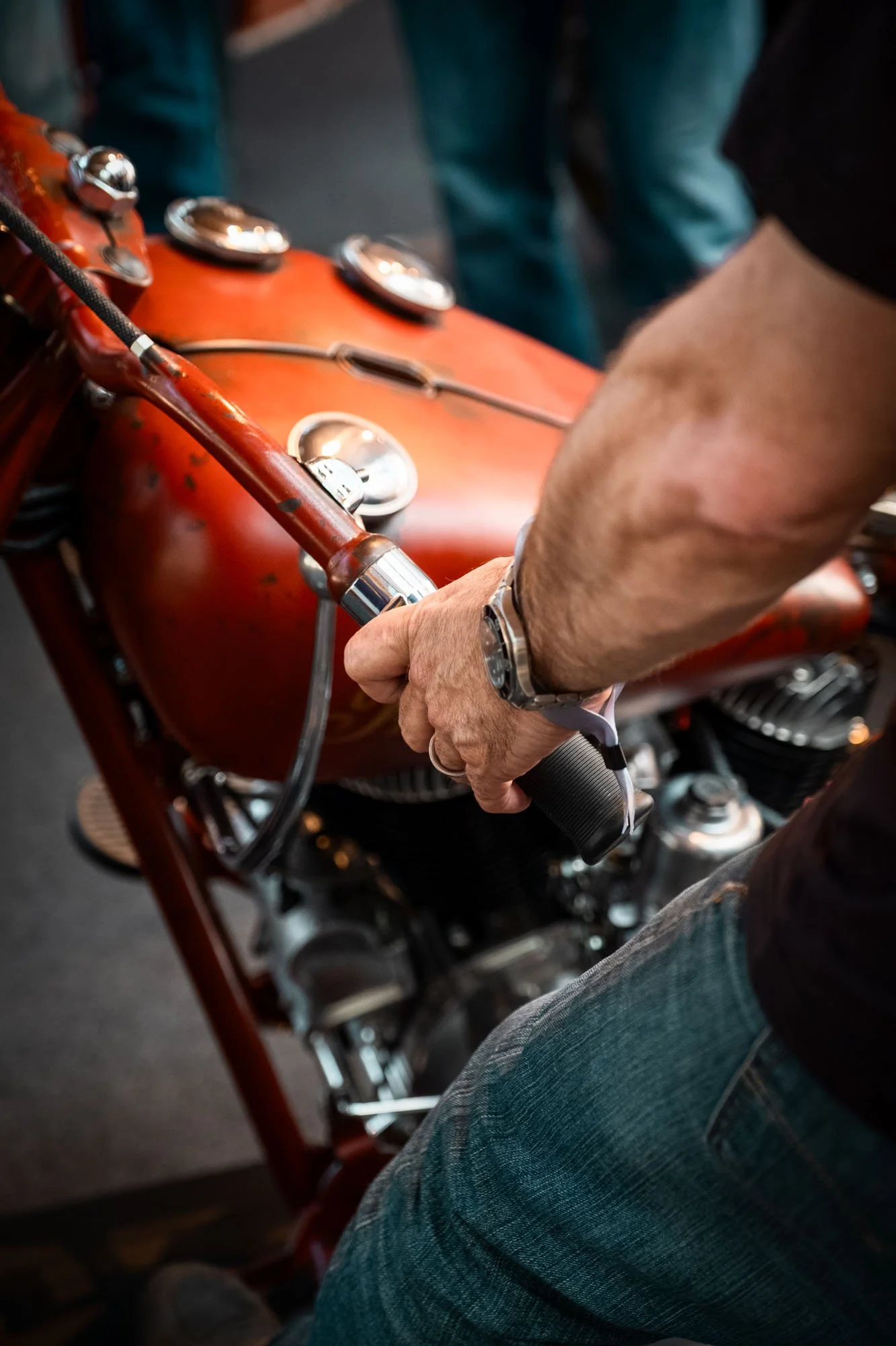 Close-up of a person gripping a throttle on a vintage red motorcycle.