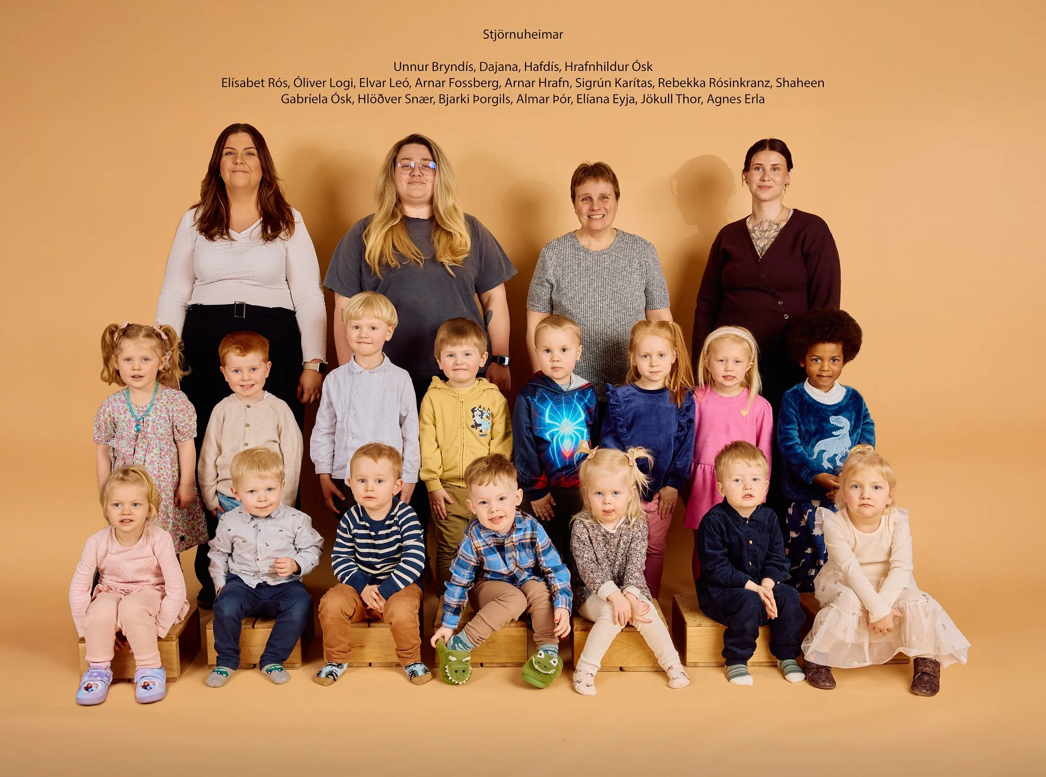 Group photo of teachers and young children in front of a yellow background, with Icelandic text above.