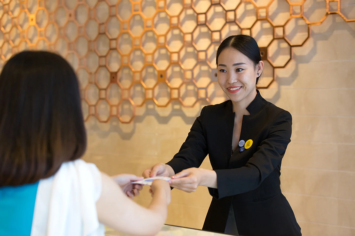 Woman Smiling and Handing Room Card to Guest