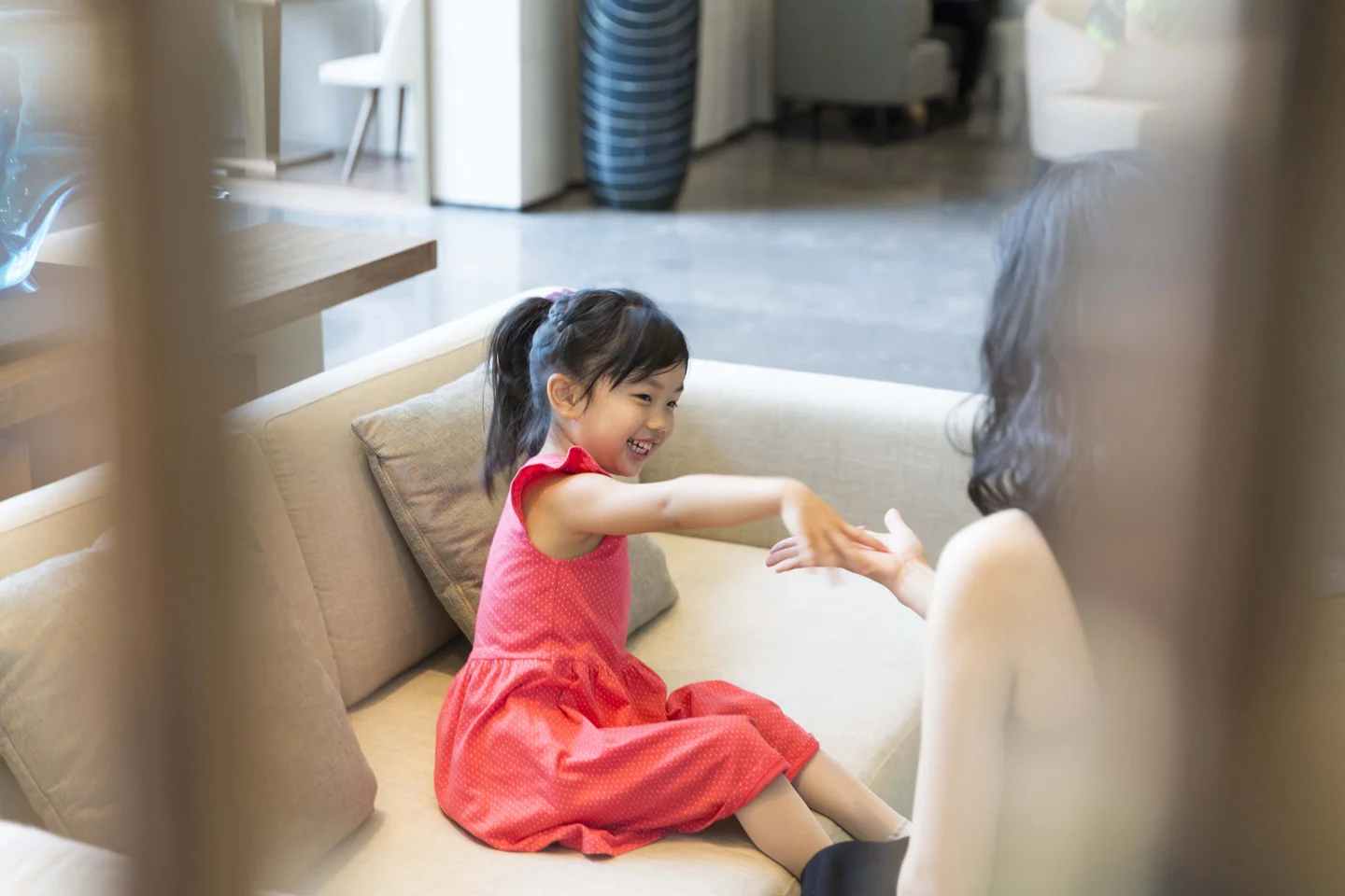 Child in Pink Dress Smiling and Sitting on Sofa