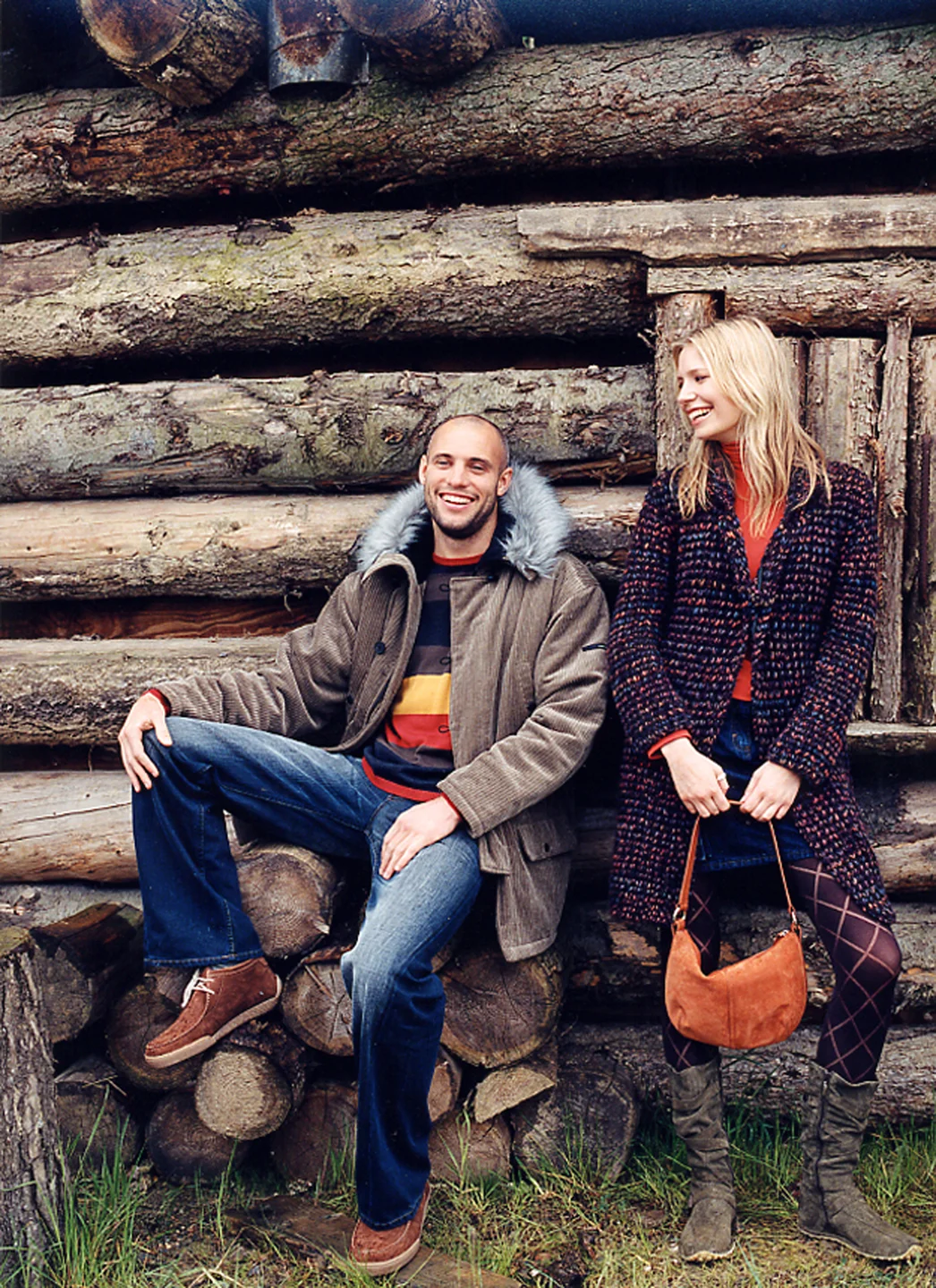 Smiling man and woman posing outside wooden cabin