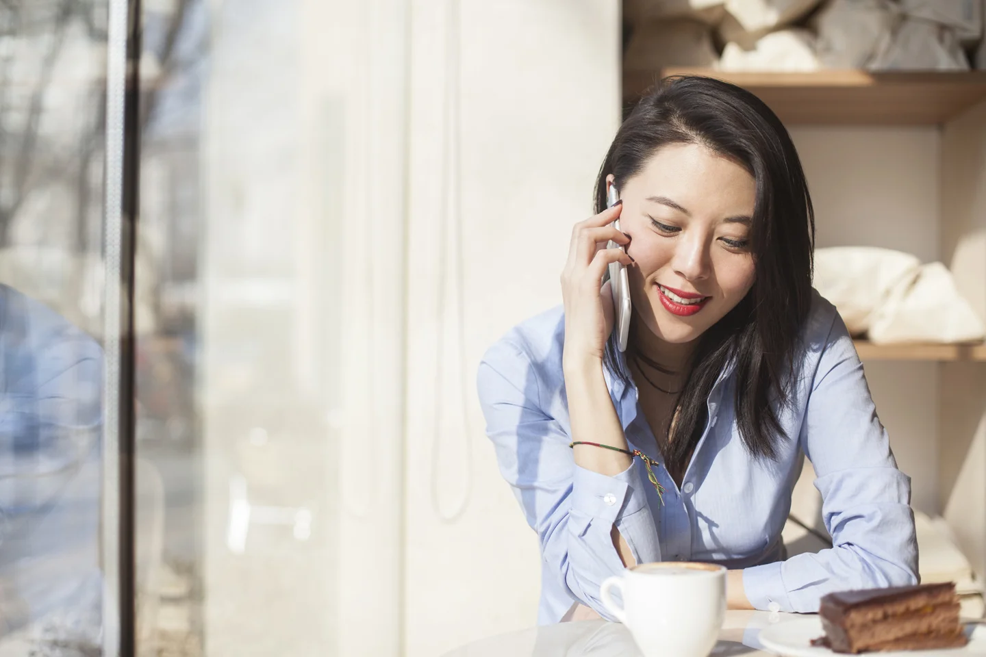 Woman with black hair sitting in cafe talking on mobile phone