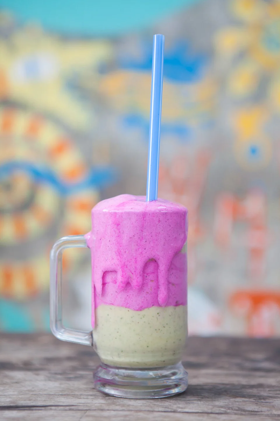 Pink and vanilla ice cream milkshake served in glass with blue straw