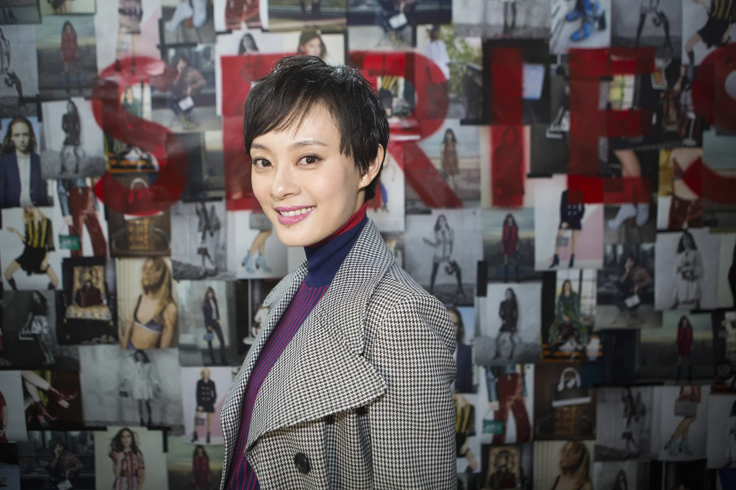 Woman smiling in front of wall of photograph collage