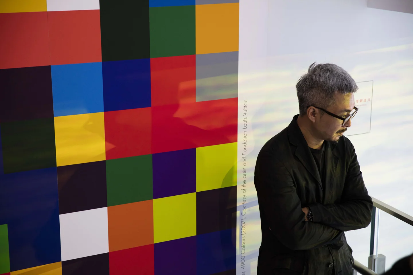 Man with grey dyed hair standing next to piece featured in art gallery