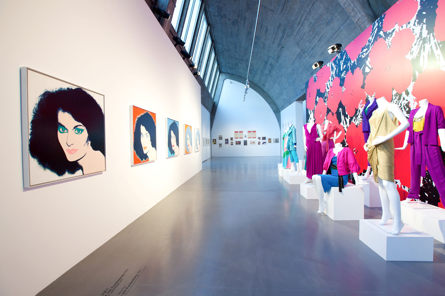 Interior of art gallery featuring pop art portraits and fashion pieces on mannequins