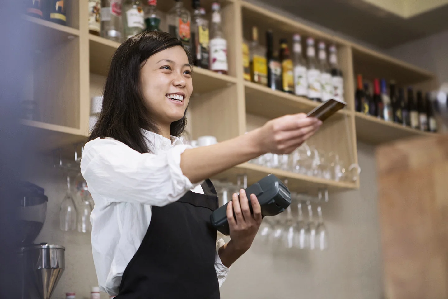 Woman with hand outstretched holding credit card and card reader