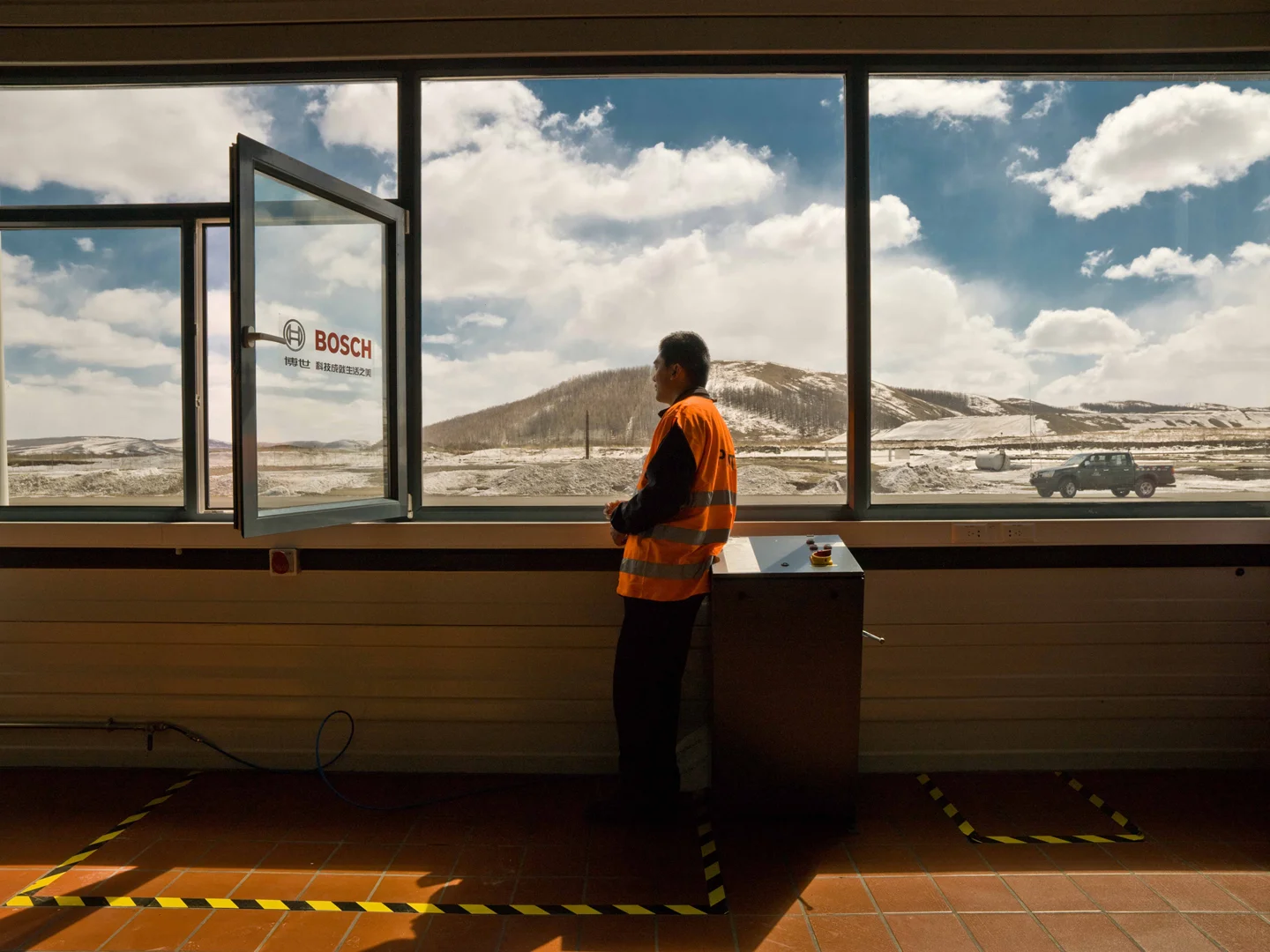 man dressed in airport freight uniform standing next to window