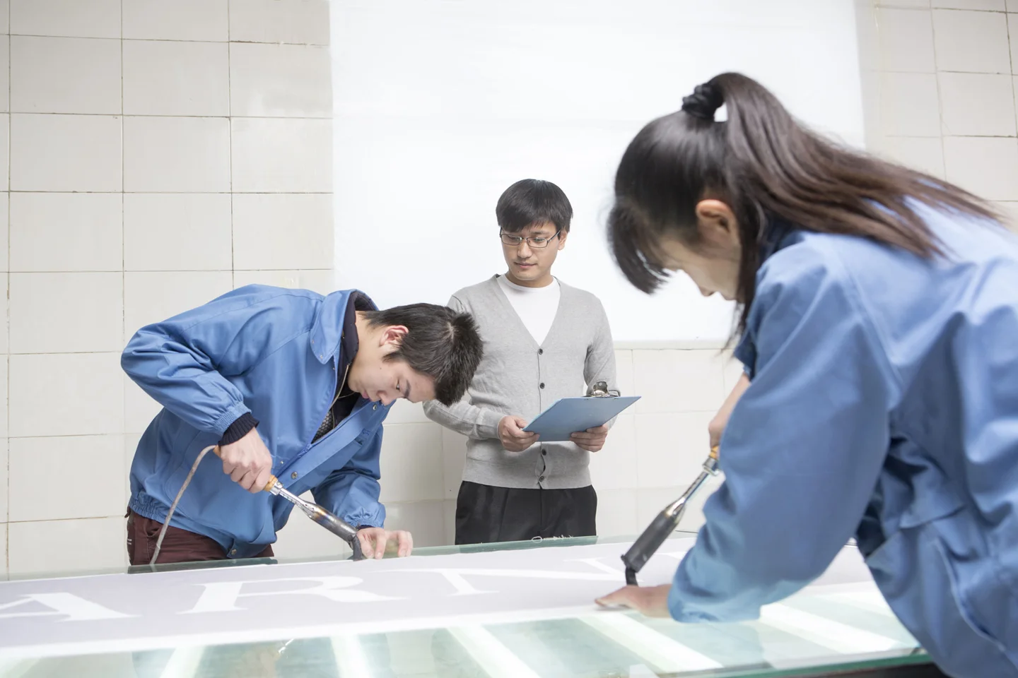 Man holding clipboard inspecting factory workers