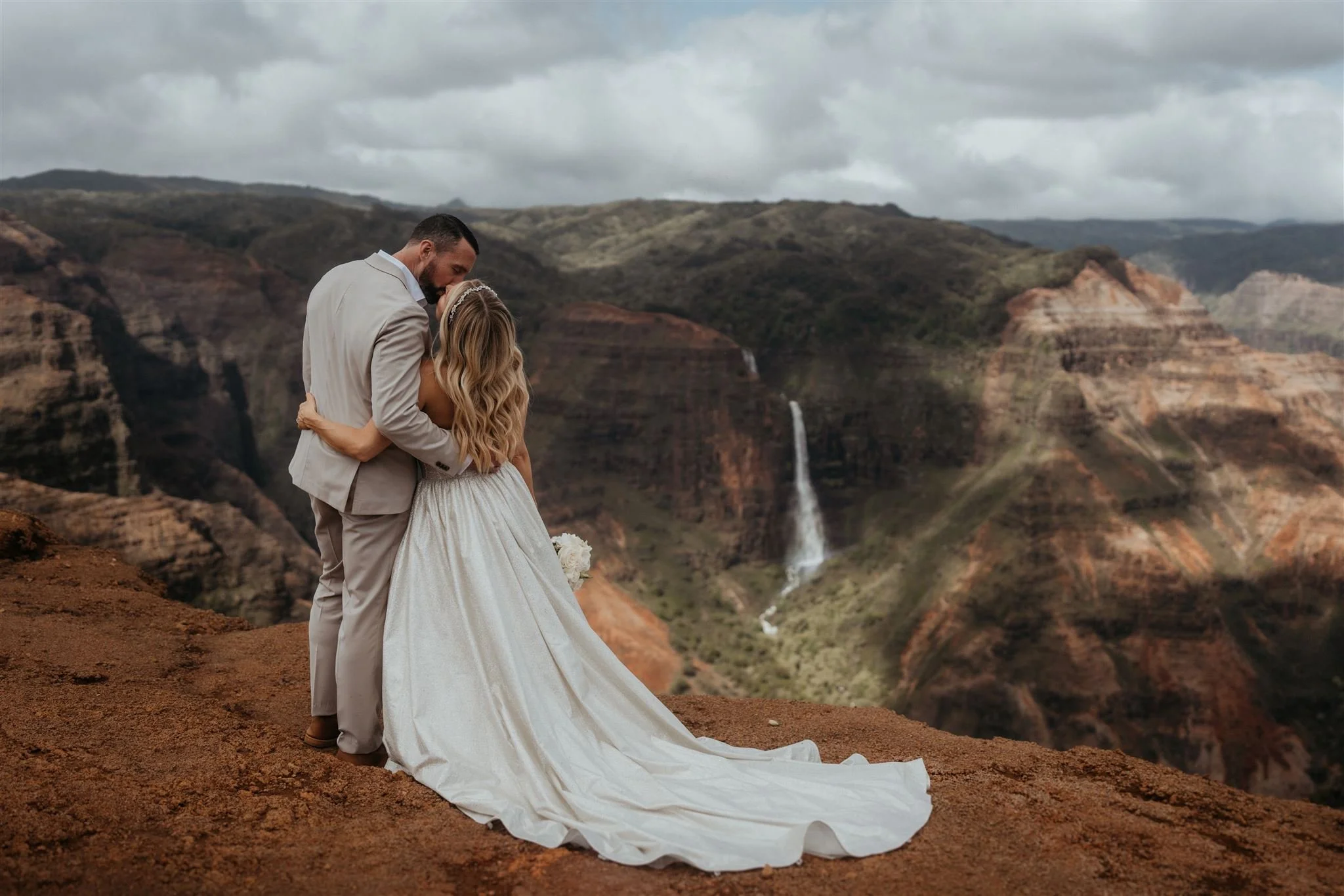 Bride and groom kiss at a canyon overlook during their elopement in Hawaii