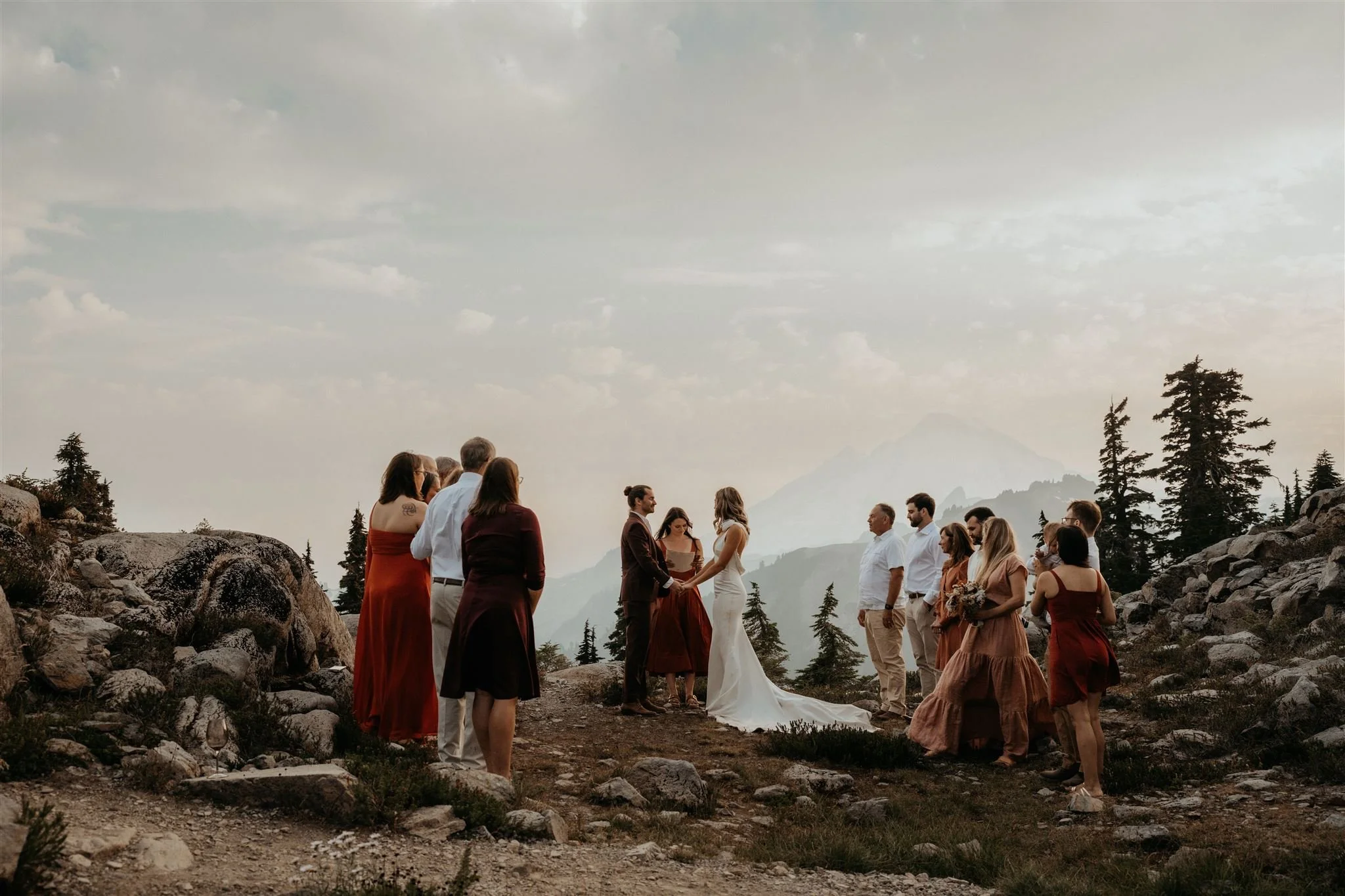 Elopement guests look on as bride and groom exchange vows in the mountains