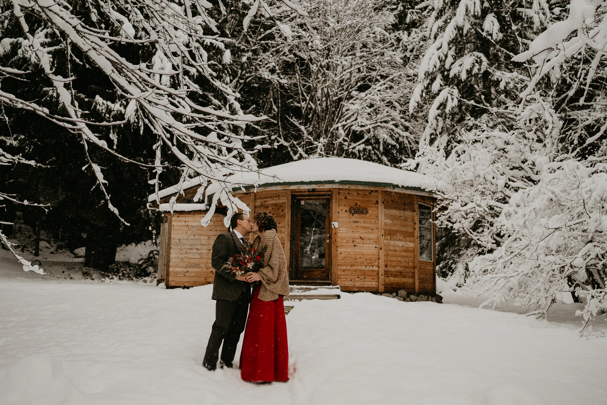 Bride and groom in front of a cozy cabin outside of Mount Rainier National Park covered in snow