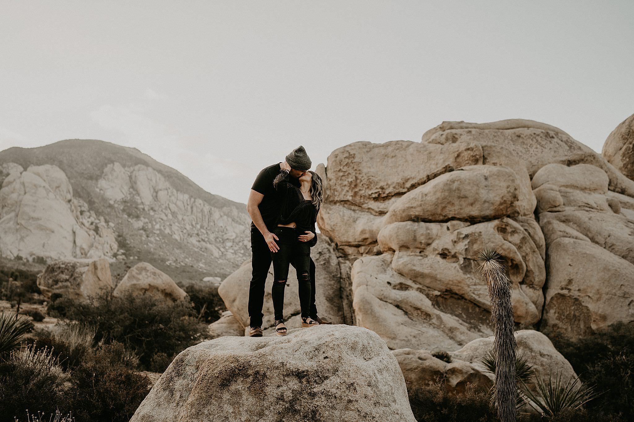 Couple standing on rocks at Joshua Tree National Park for their engagement photos