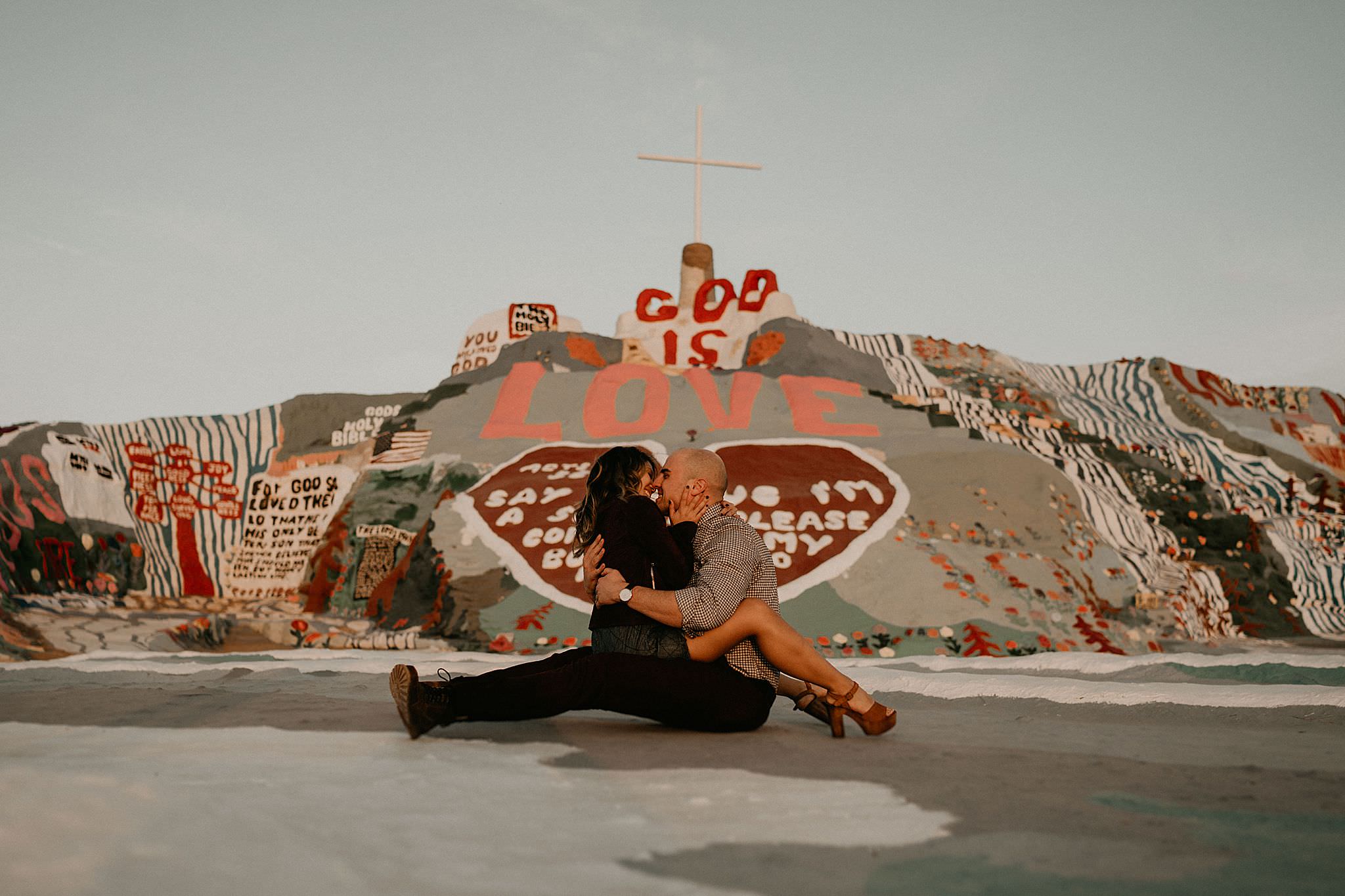 Couple kissing at salvation mountain for engagement photos