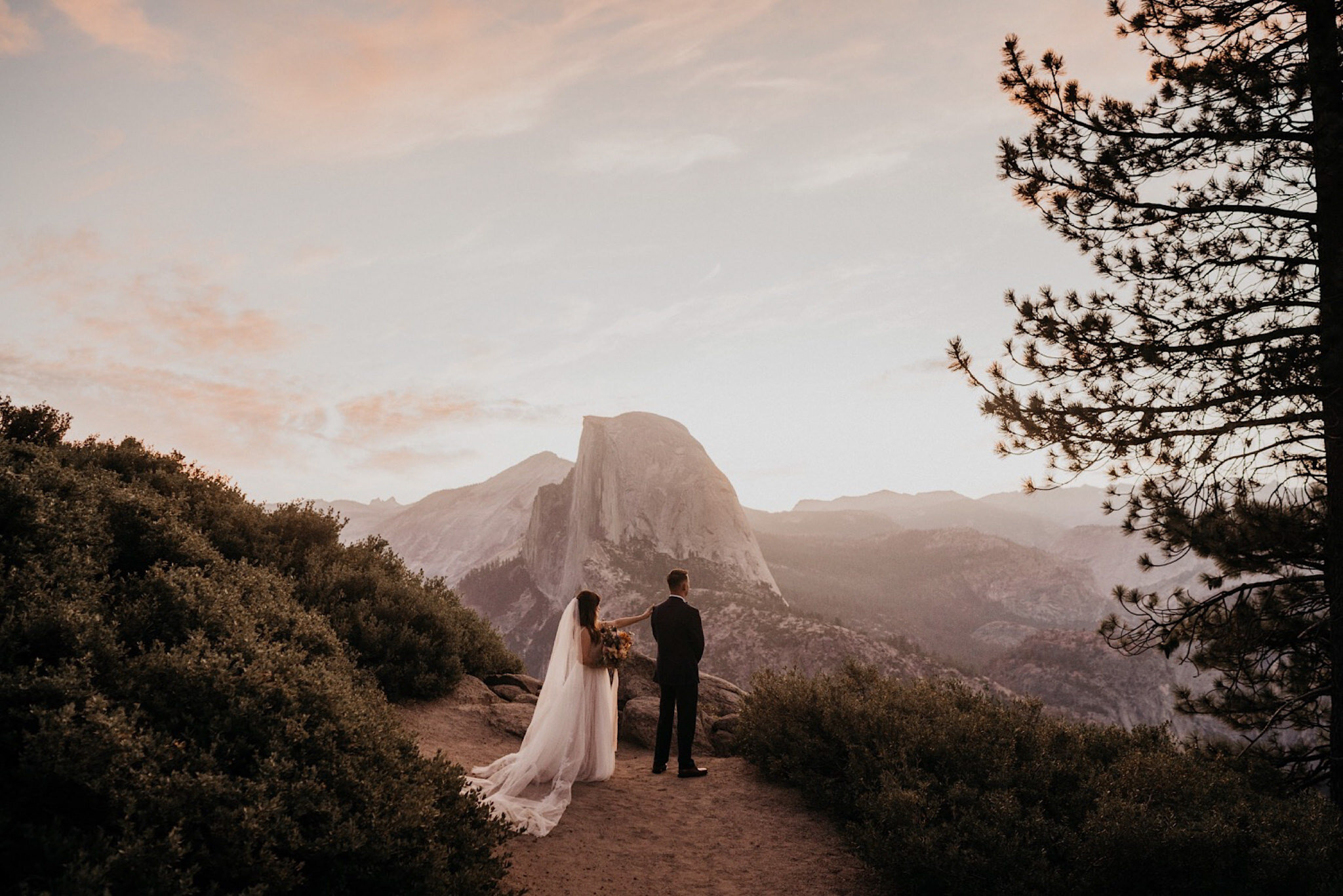 Bride and groom during their first look on Glacier Point in front if Half Dome during their elopement photography
