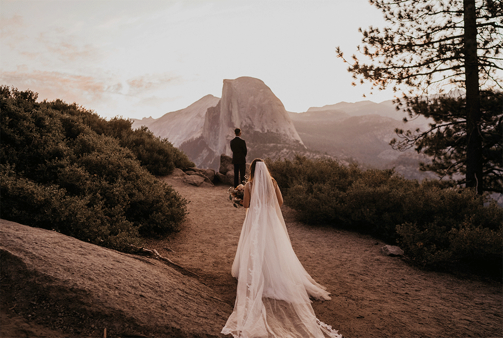 Bride and groom during their first look on Glacier Point in front if Half Dome during their elopement