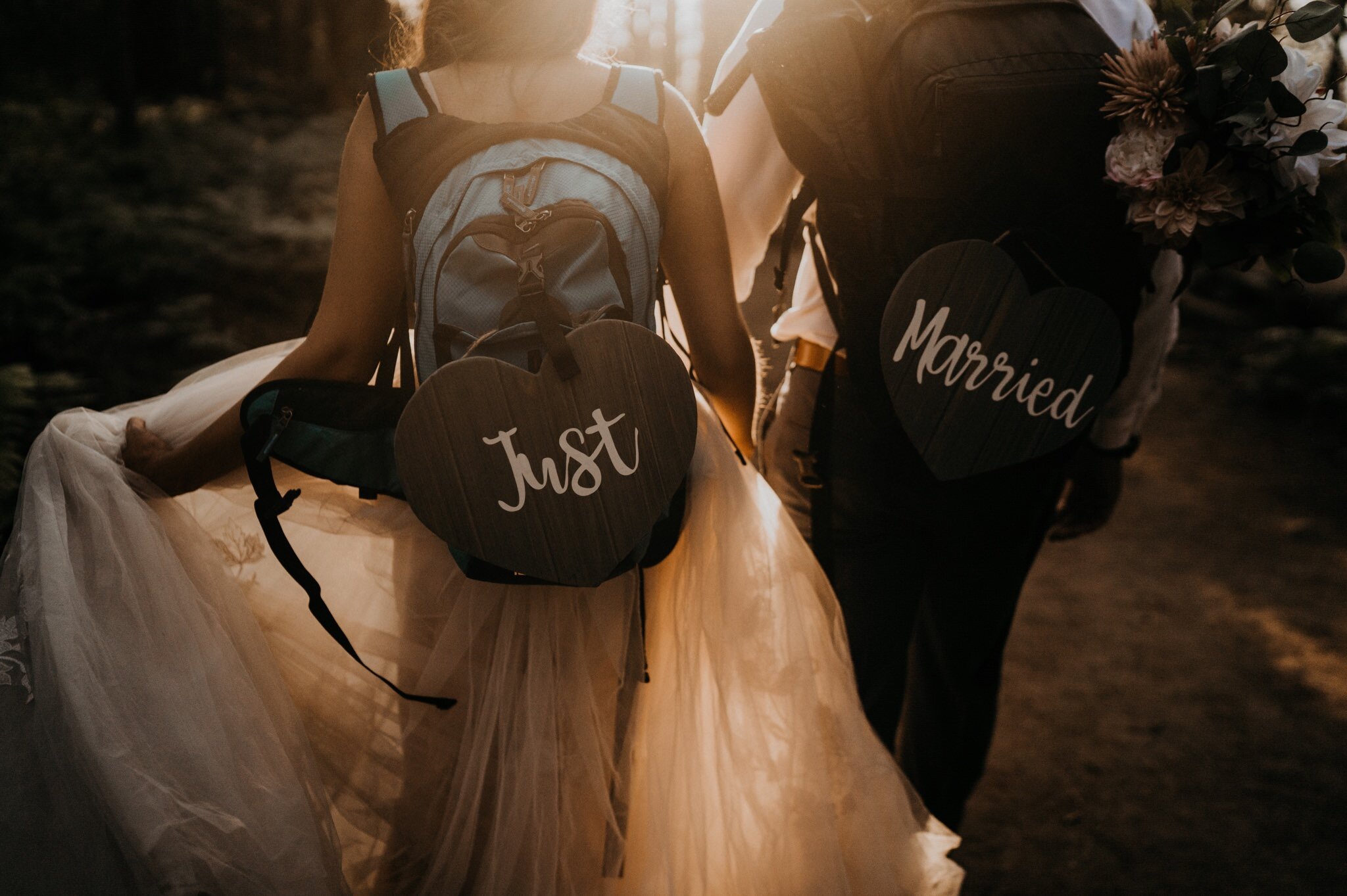 Married couple hiking with "Just Married" sign to Taft Point for sunset photos on their Elopement Day at Yosemite National Park