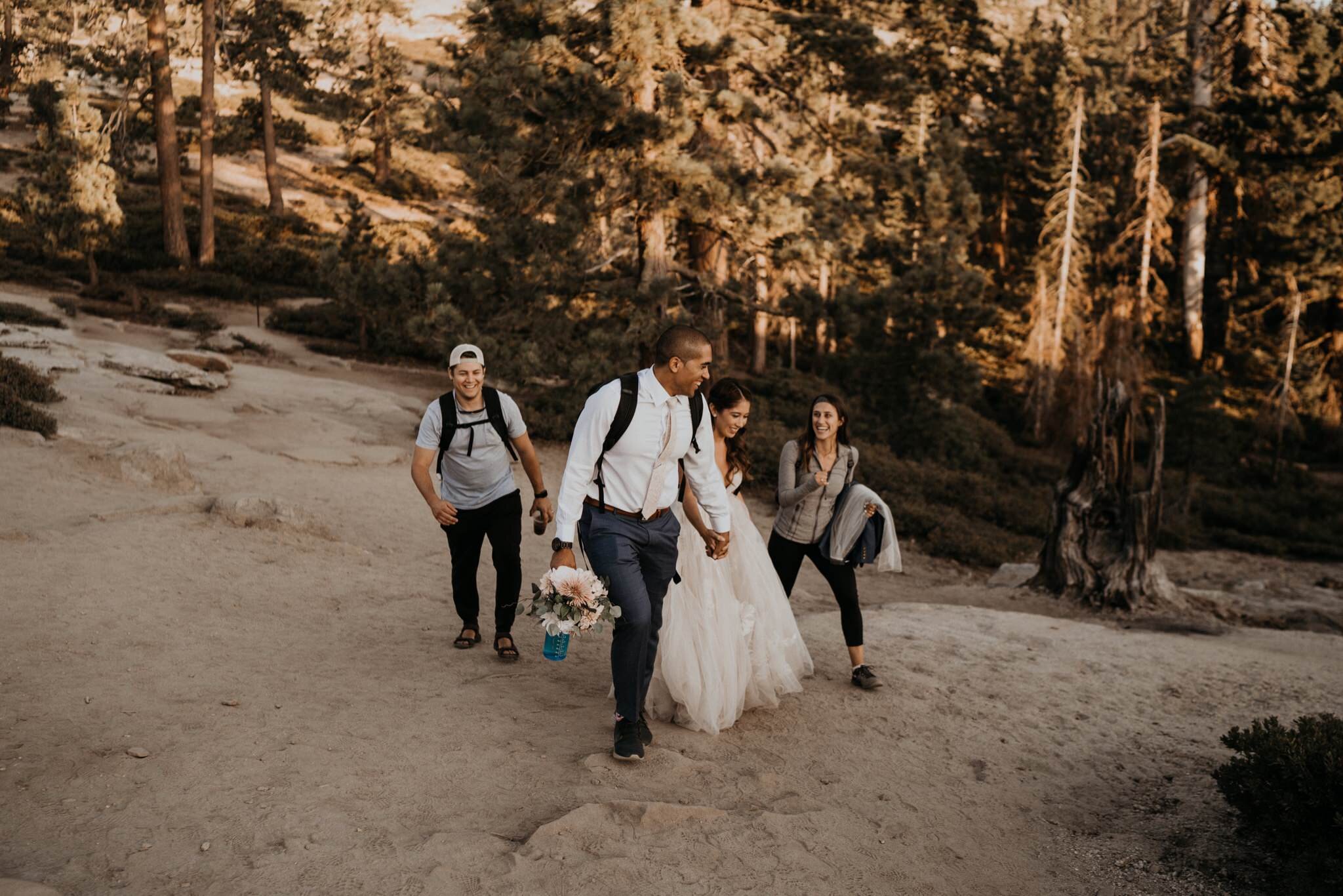 Married couple hiking with "Just Married" sign to Taft Point for sunset photos on their Elopement Day at Yosemite National Park