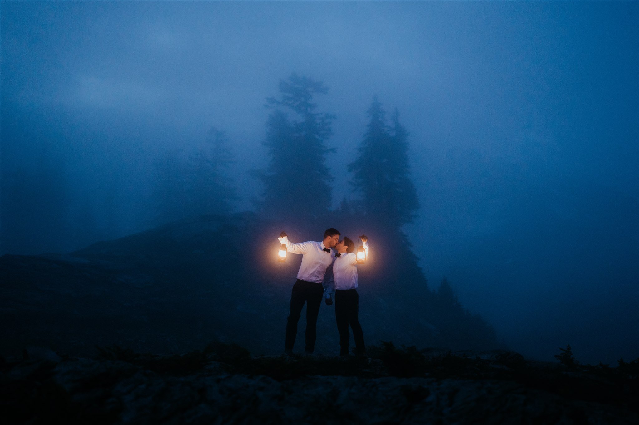 Two grooms holding lanterns during sunrise in the North Cascades mountains