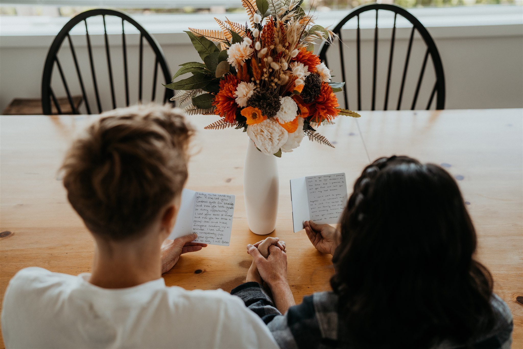 Two brides reading vow books on their elopement morning