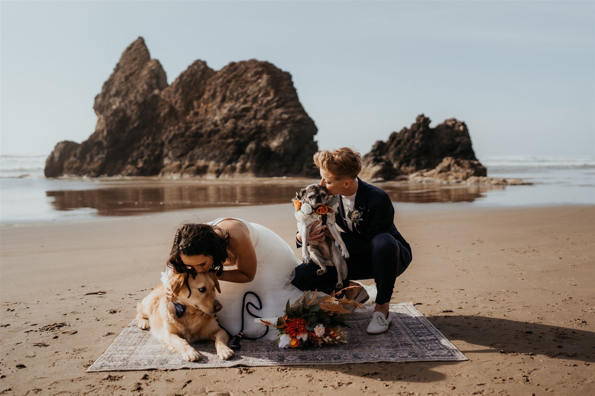 Two brides kiss their two dogs on the Oregon coast