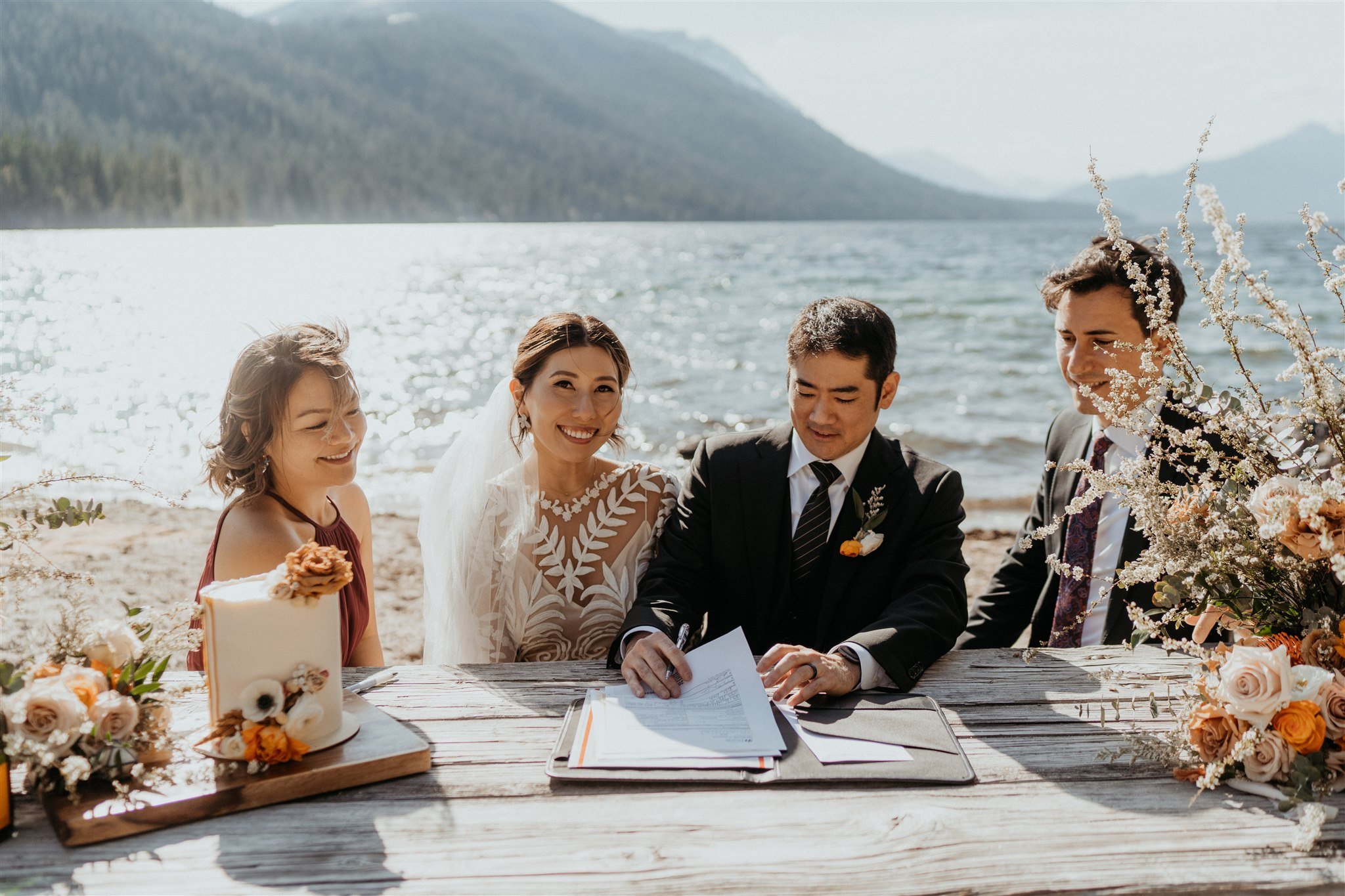 Bride and groom sign the marriage certificate with friends at their Lake Wenatchee elopement