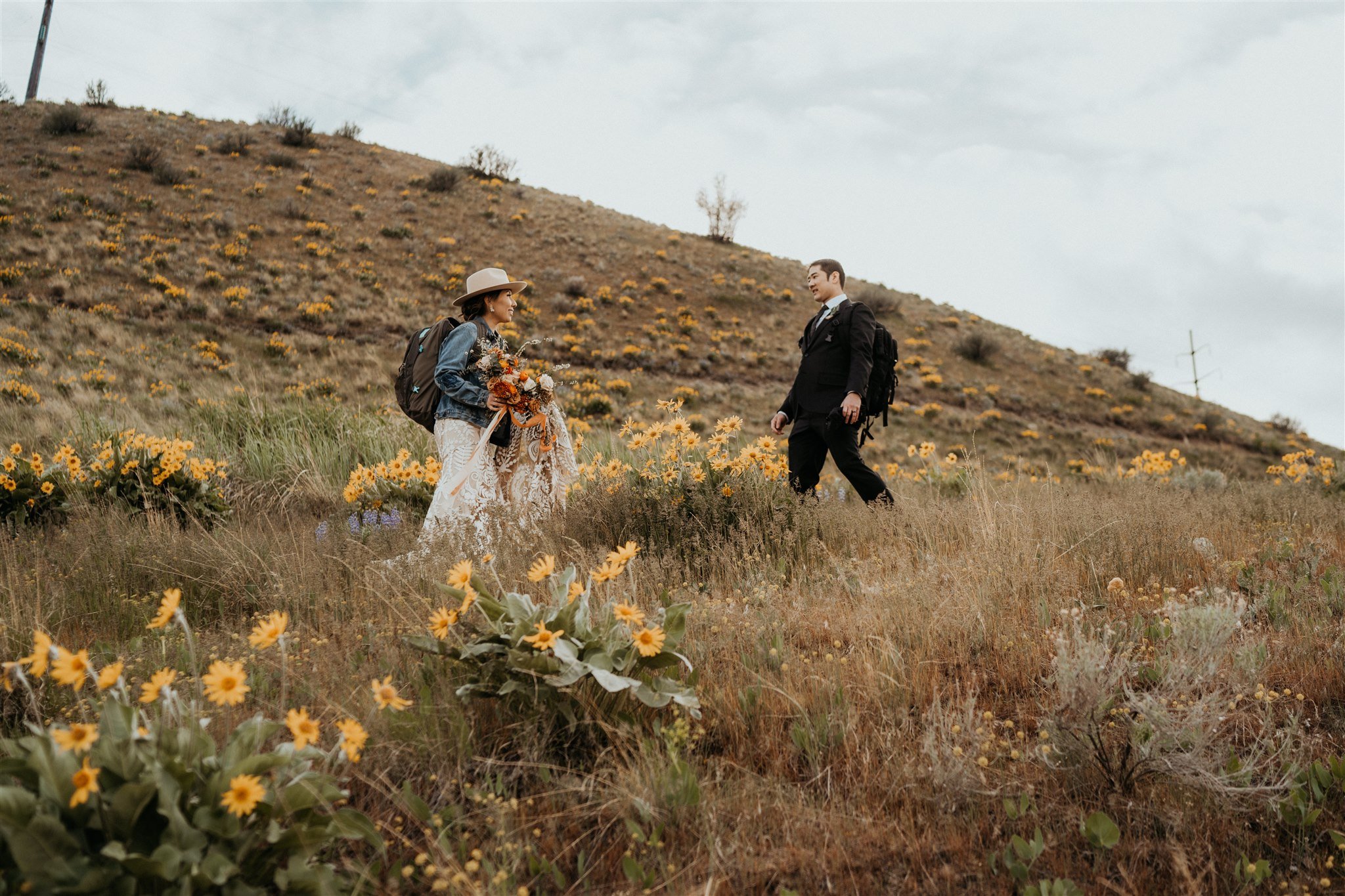 Bride and groom walking through a wildflower field trail in the North Cascaces