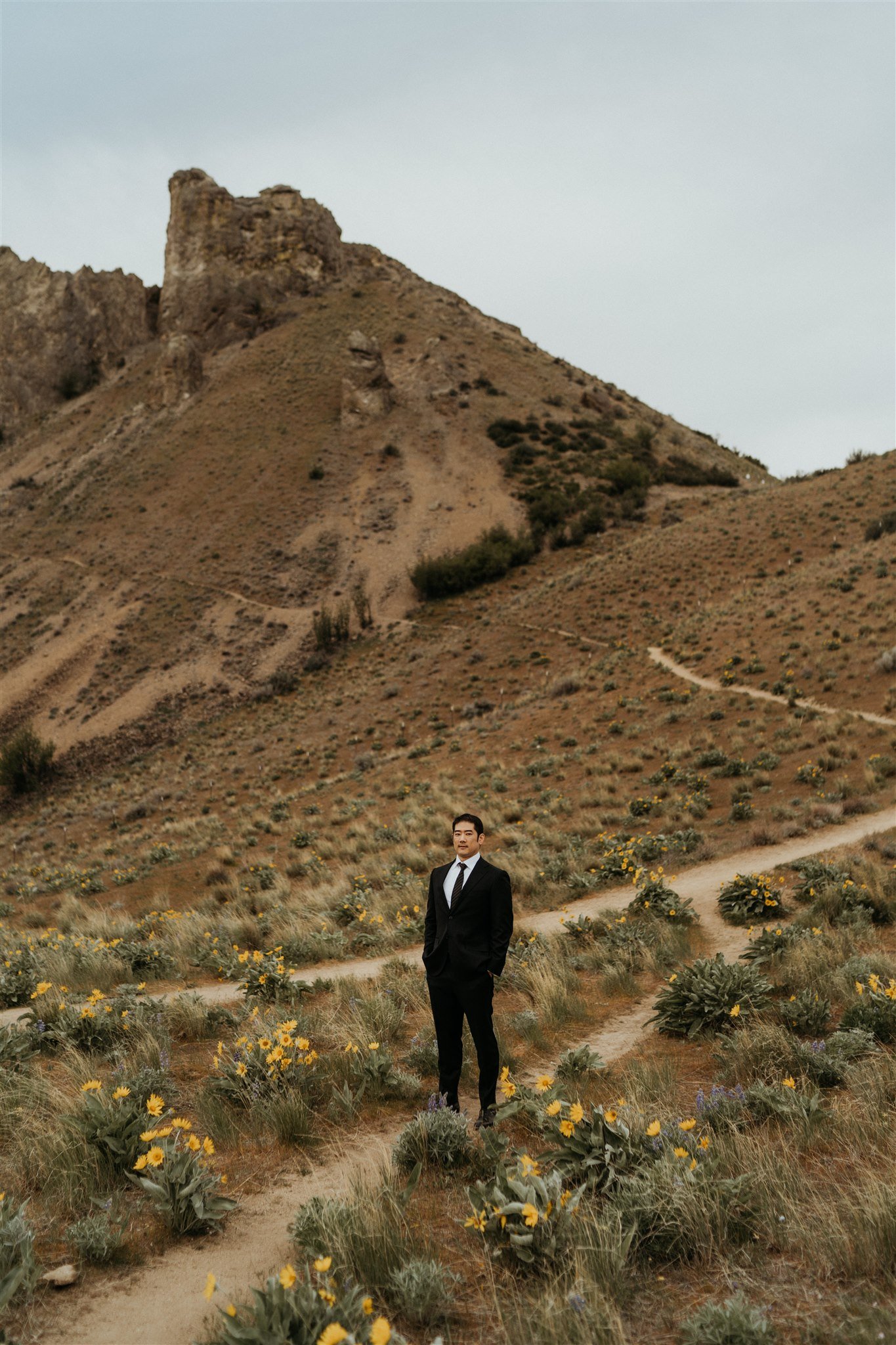 Groom wearing a black suit on a hiking trail in the North Cascades